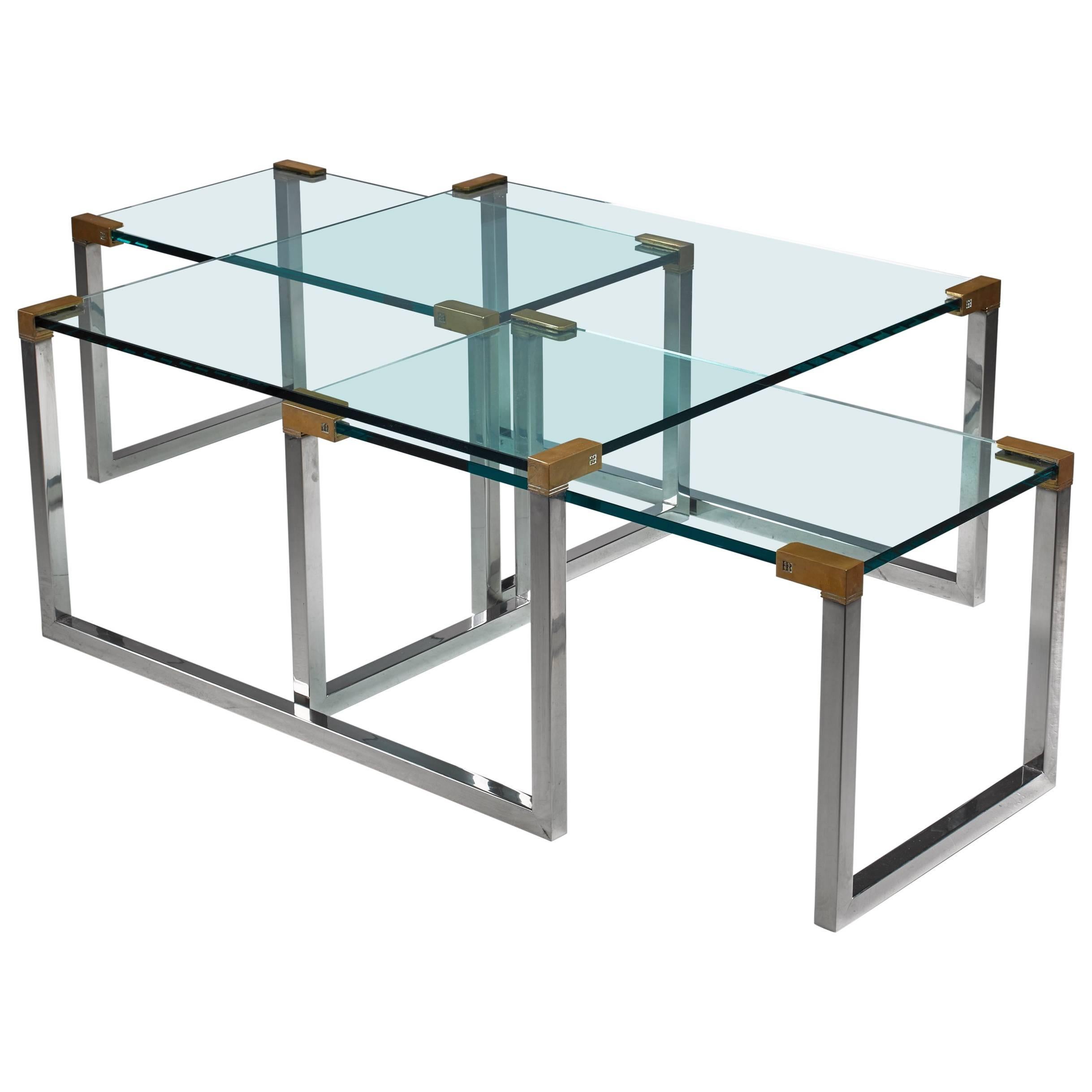 A set of three modular side or coffee tables by Dutch-Hungarian designer Peter Ghyczy. The tables are made of a chrome and brass frame with a glass top.

The measurements stated are of the large table. The two smaller tables are 45 by 83 cm and 42