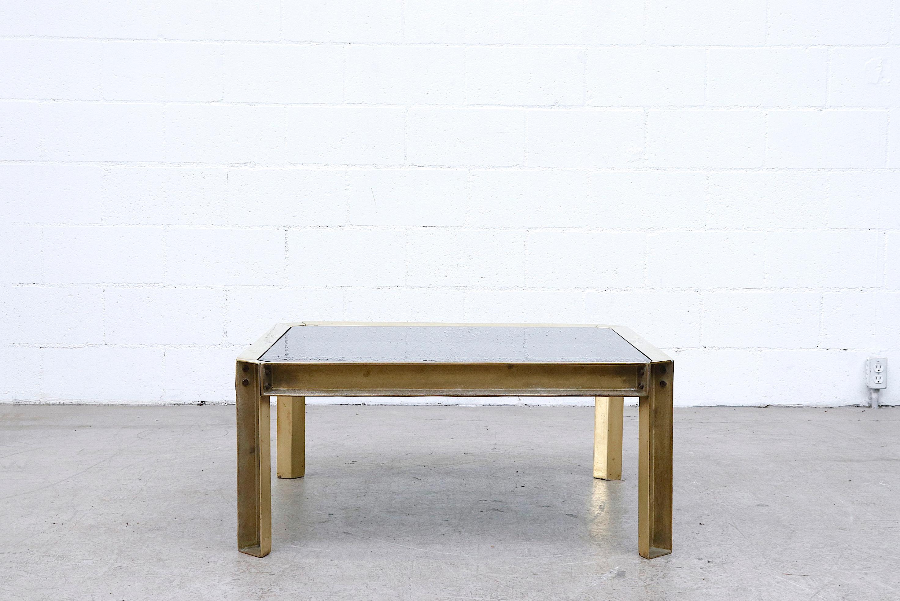 Midcentury Industrial brass frame and smoked glass coffee table with raw construction appearance. In original condition with some visible wear, small chips to the glass and nice patina. Peter Ghyczy studied architecture with an industrial design