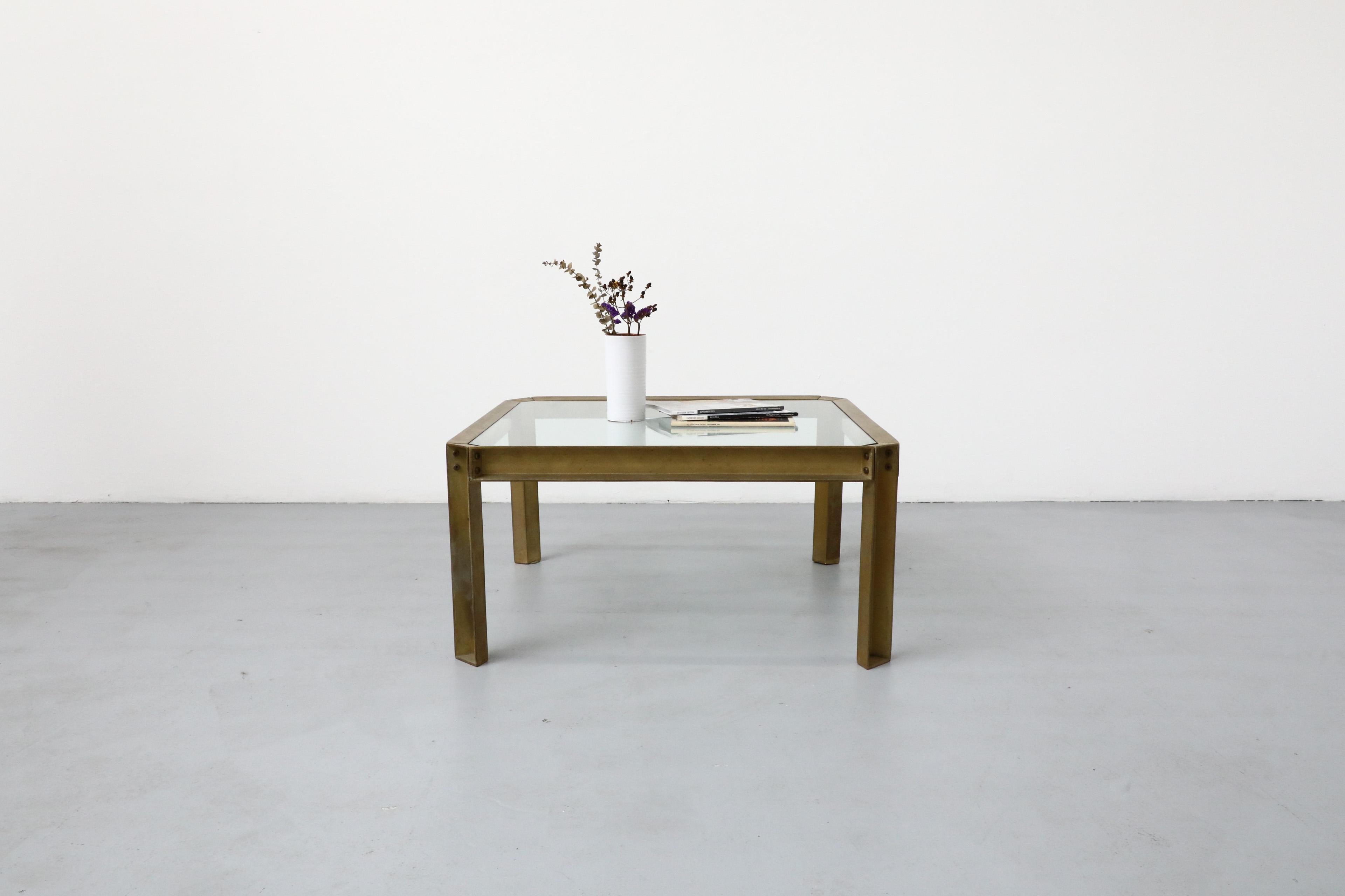 Quadratischer Couchtisch mit Glasplatte und einem Gestell aus rohem und poliertem Messing, das ihm einen industriellen Charakter verleiht. Im Originalzustand mit schöner Patina. Entworfen von Peter Ghyczy. Ghyczy studierte Architektur mit einem