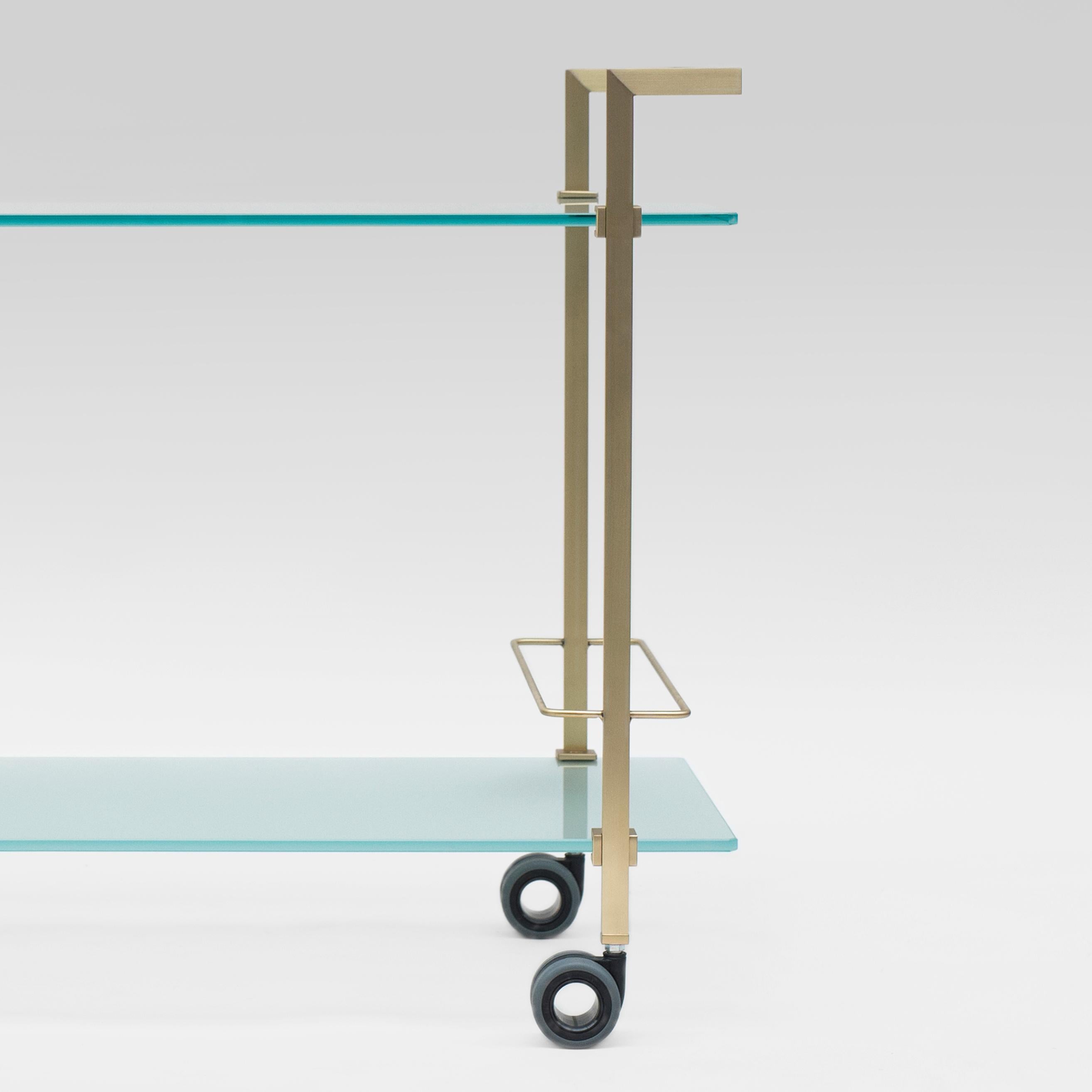 Tea Trolley designed by Peter Ghyczy in 2004.
Manufactured by Ghyczy (Netherlands)

This slender tea trolley is a piece of art on its own. Two tempered glass plates connect the metal frames. Small cast metal details secure the transparent