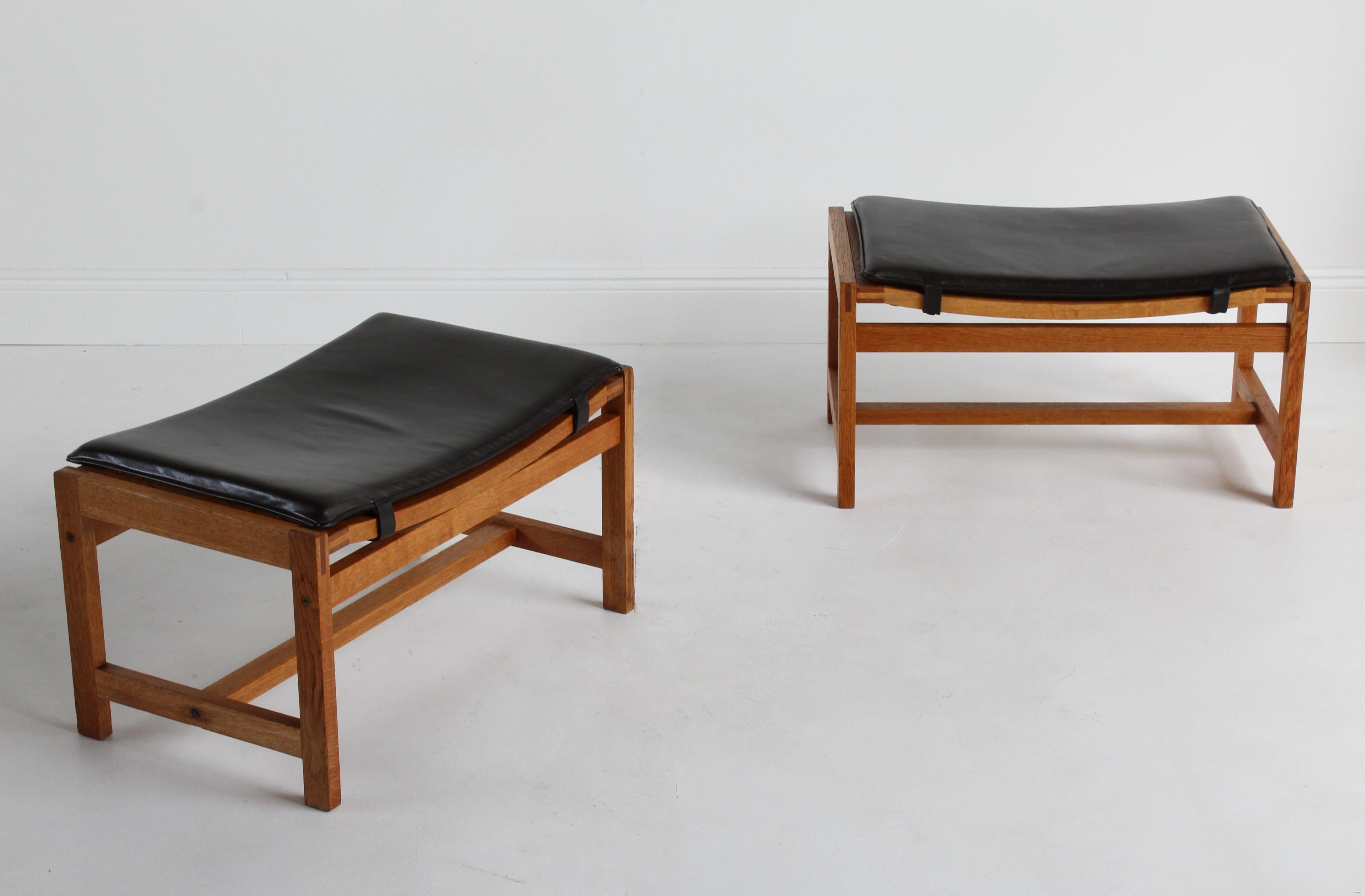 A pair of stools / ottomans designed by Peter Hjorth and Arne Karlsen in 1959. Produced by Interna, and executed in oak, with the original webbed cane, and black dyed leather. Bears brass label. Production is of high-level craftsmanship and quality