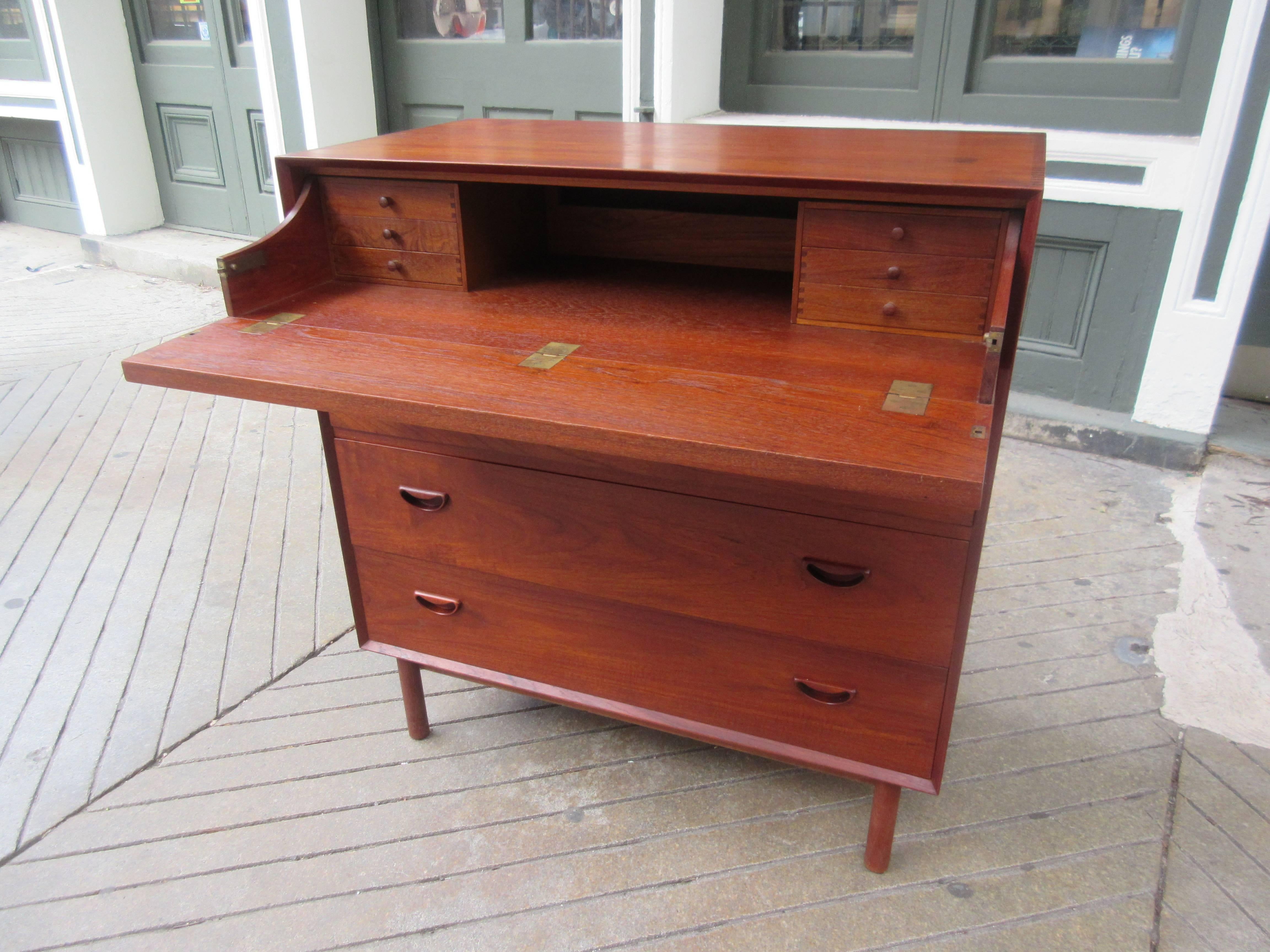 Peter Hvidt and Orla Mølgaard- Nielsen teak drop front desk with three drawers for John Stuart. Drop front reveals writing surface and six small drawers for small items. Recessed brass hinges provide a totally flat surface. Legs are canister style