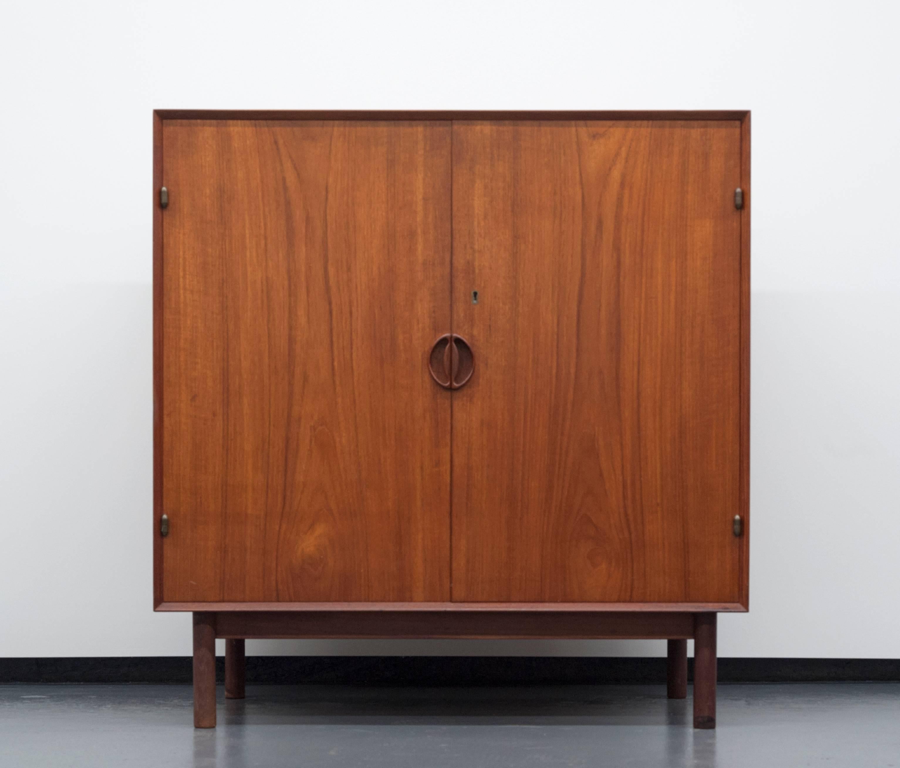 Beautiful solid teak cabinet by Peter Hvidt and Orla Mølgaard-Nielsen. Exceptional quality and functional piece. Finger joints with solid brass hardware. Original receipt dates to 1962. Two doors open to reveal three drawers and one adjustable