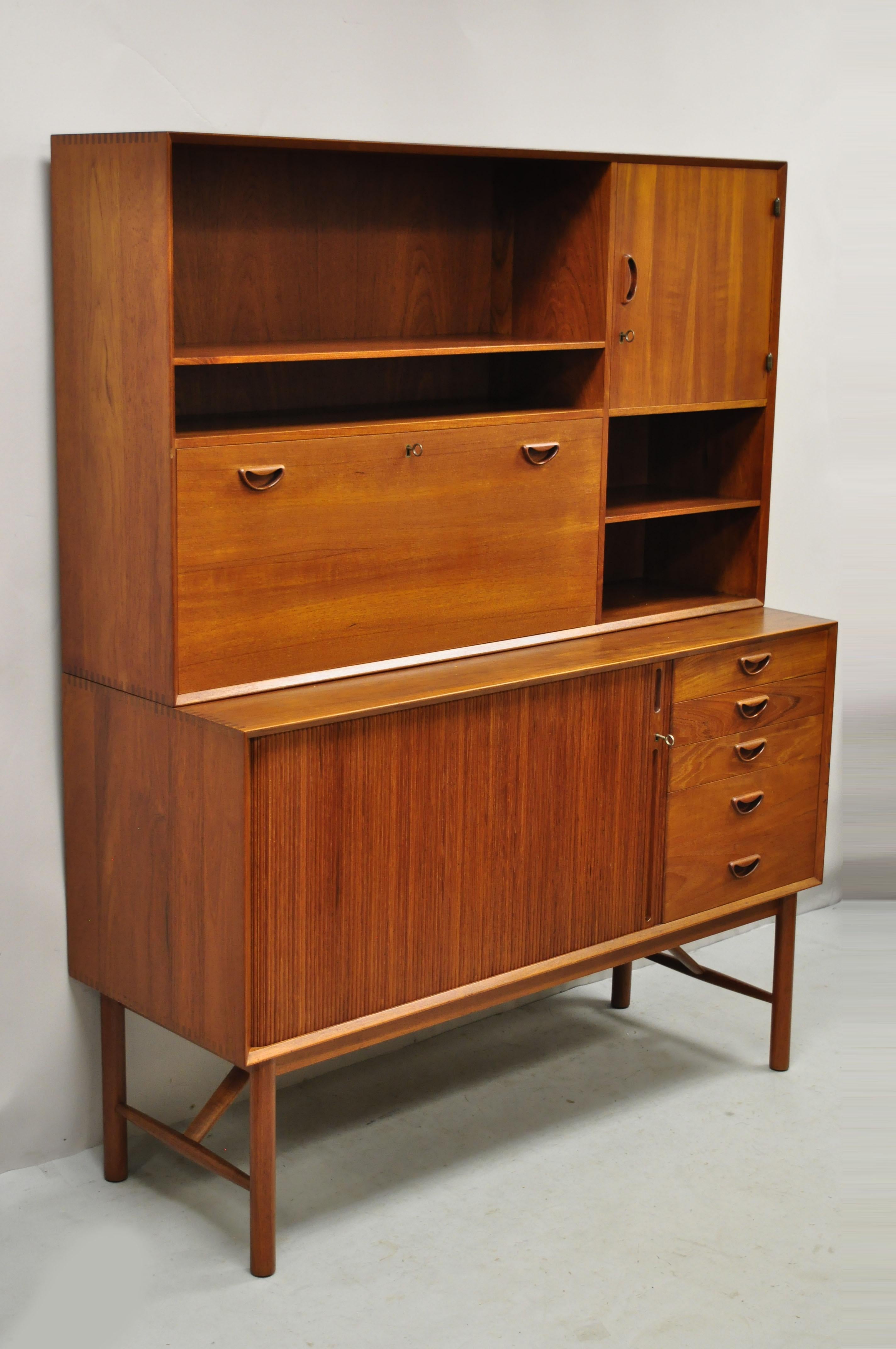 Peter Hvidt and Orla Molgaard Nielsen Teak Tambour Door Bookcase Hutch Credenza Cabinet. Item features tambour sliding door, unique raised stretcher base, exposed joinery to case, hutch top with fall front, 2 part construction, working lock and key,