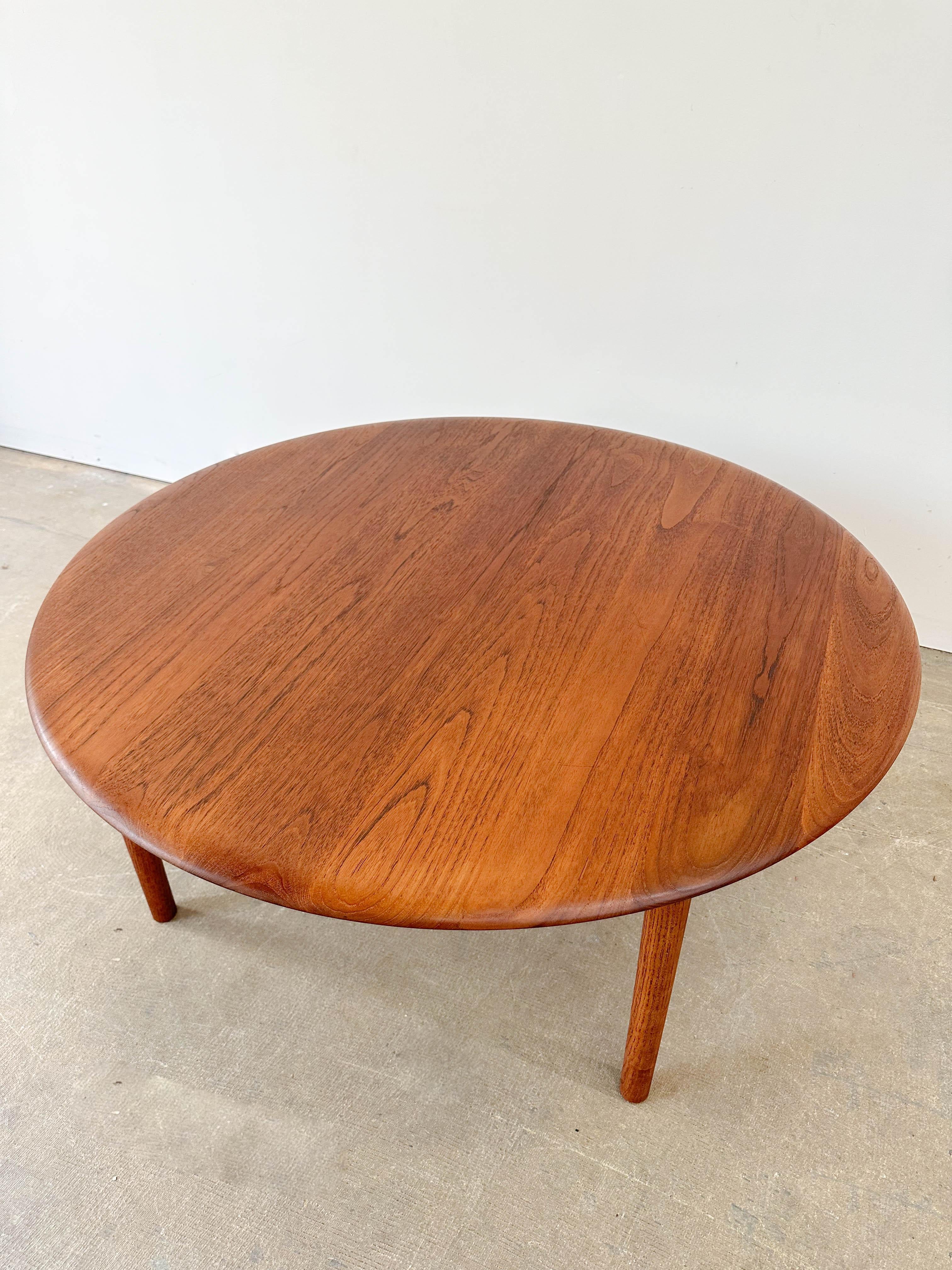 Danish modern coffee table designed by Peter Hvidt and Orla Molgaard-Nielsen for France and Son in the 1950s. Rare solid teak top is absolutely gorgeous with a rich range of teak hues and a wonderful rounded edge. Table is in very good condition.