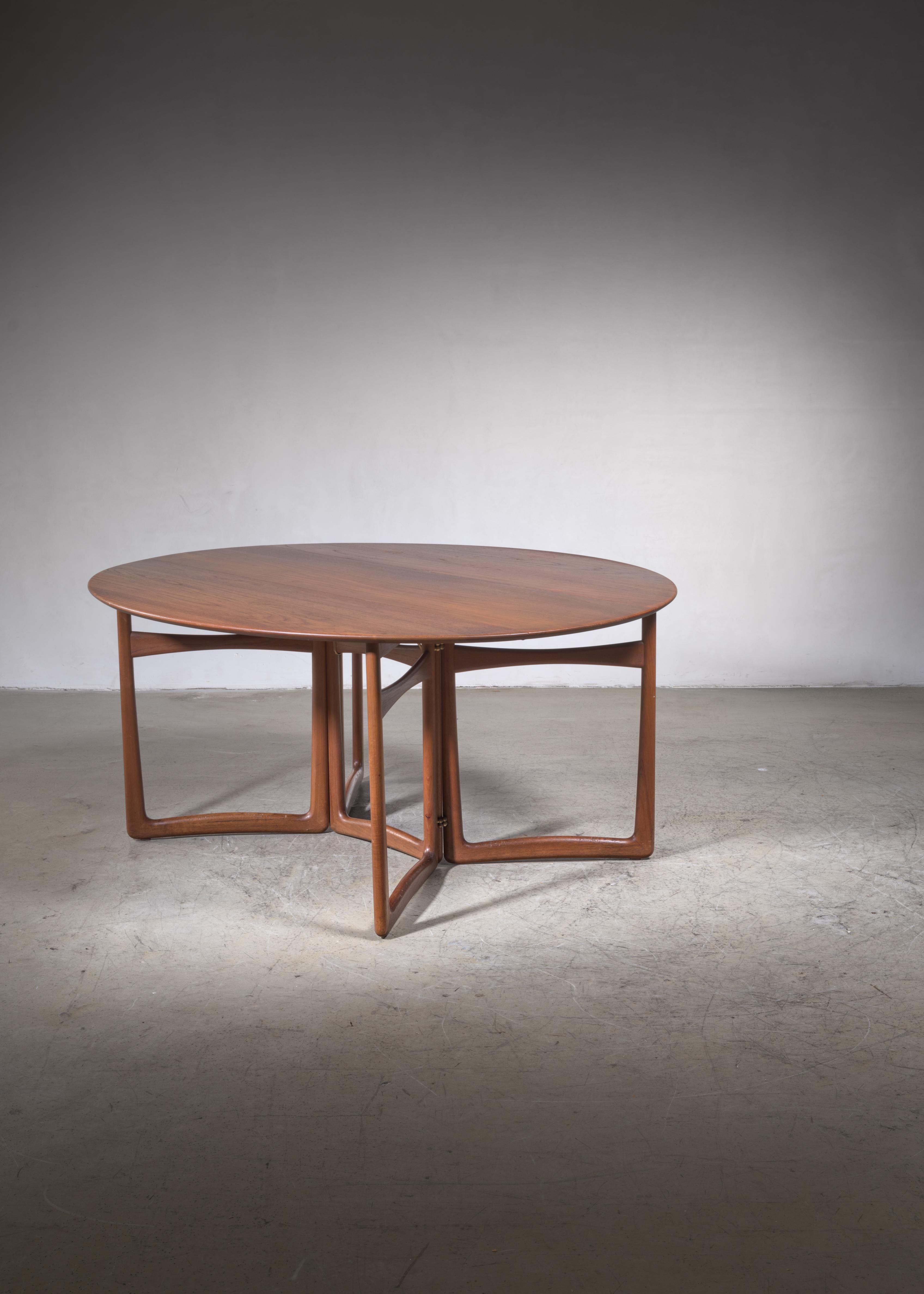 An oval, drop-leaf teak desk or dining table with brass elements is designed by Peter Hvidt and Orla Mølgaard Nielsen for France & Son, Denmark. It is labeled and in a great condition. 

The dimensions stated are of the table with both leaves