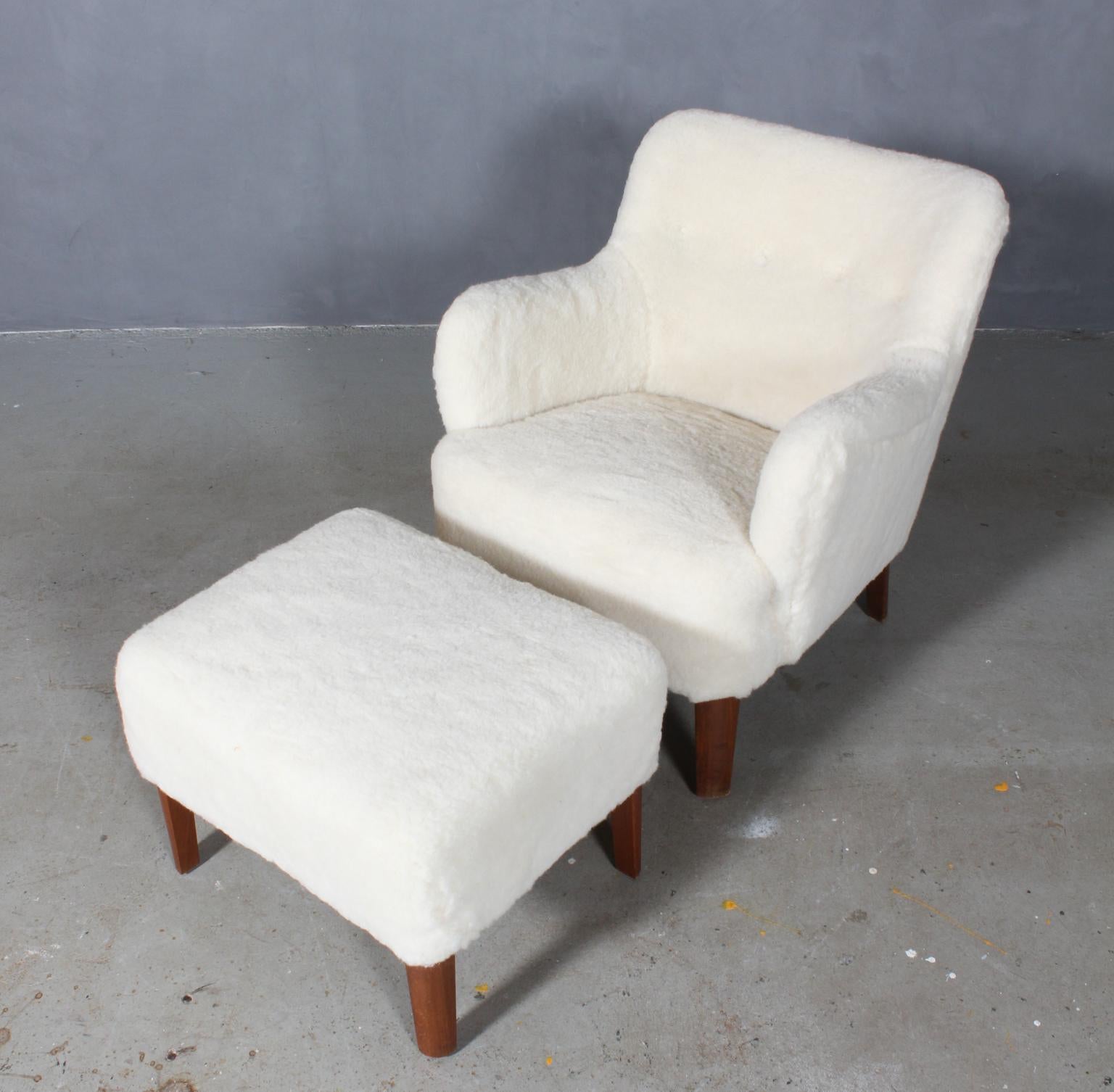 Peter Hvidt early lounge chair and ottoman new upholstered with lambskin with buttons.

Legs of stained beech.

Model 1748, made by Fritz Hansen.