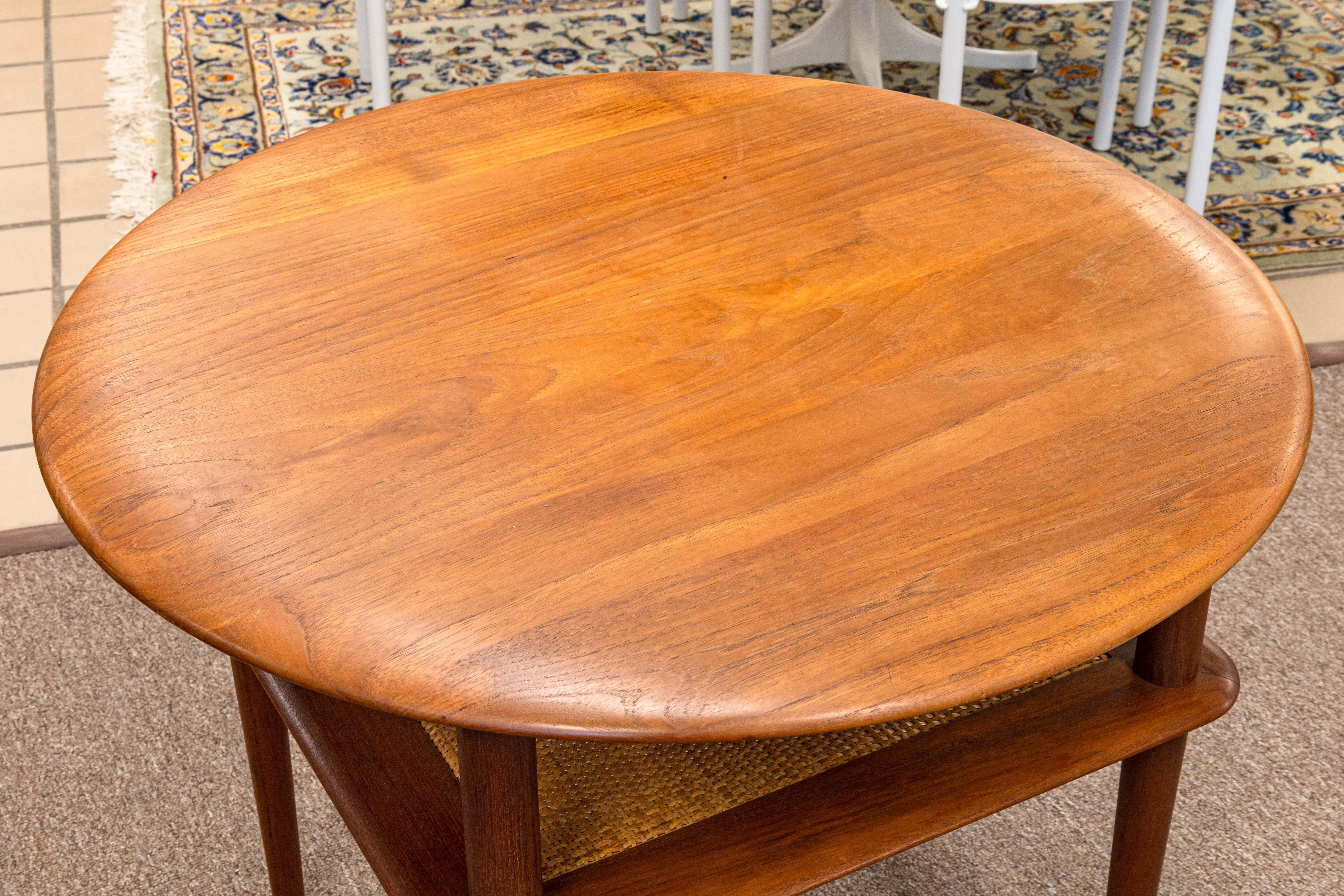 A Peter Hvidt for John Stuart side end table. A beautiful piece of mid century modern Danish furniture. This table features a teak wood construction with cane accent details. The round top of this table shows off the lovely wood grain, and below