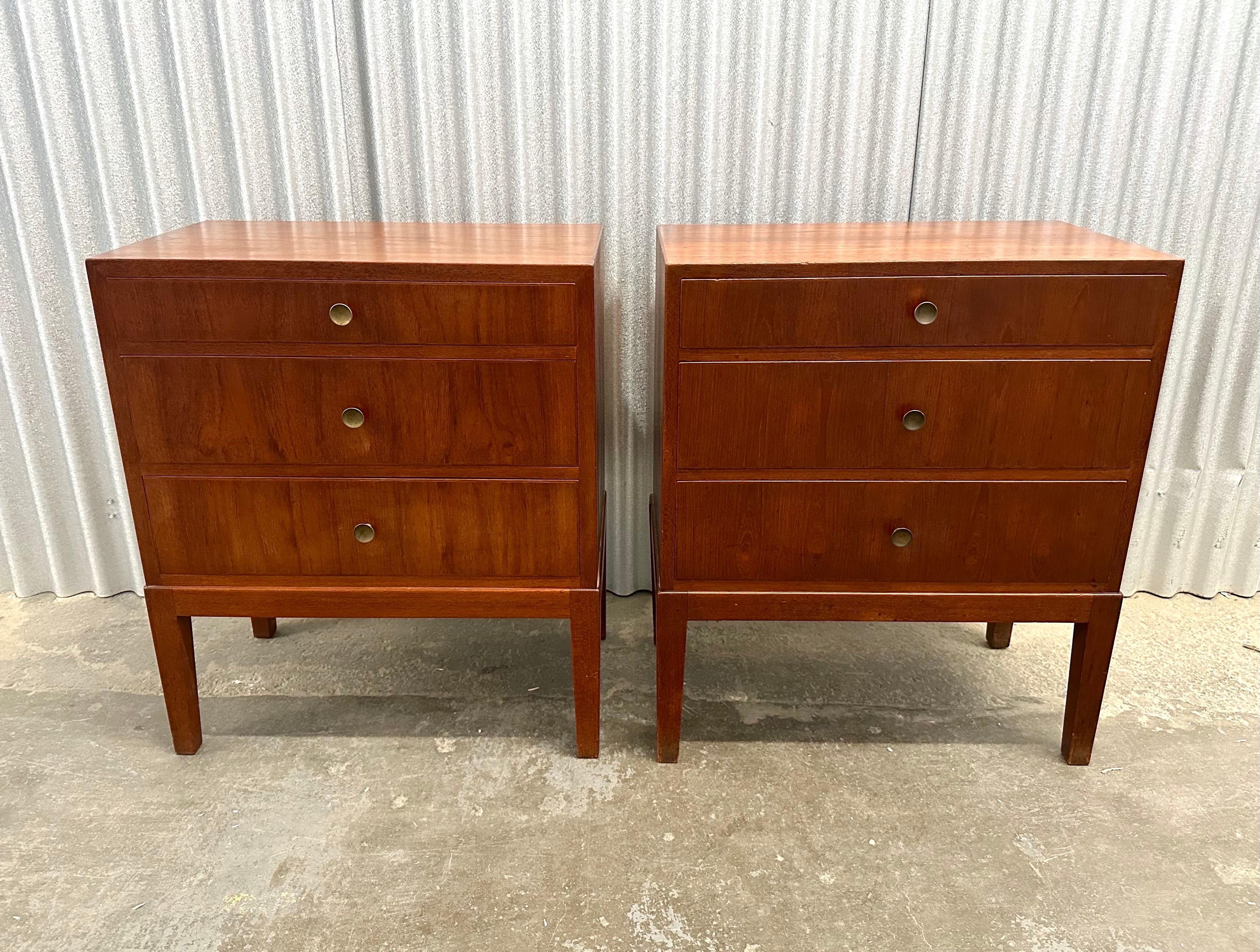 Pair of small chests of drawers in teak over birch. Slightly tapering body, brass pulls, and wonderful dark patina add to the overall elegance. A versatile size, the pair work well as nightstands, end tables, entryway consoles or silver drawers.  
