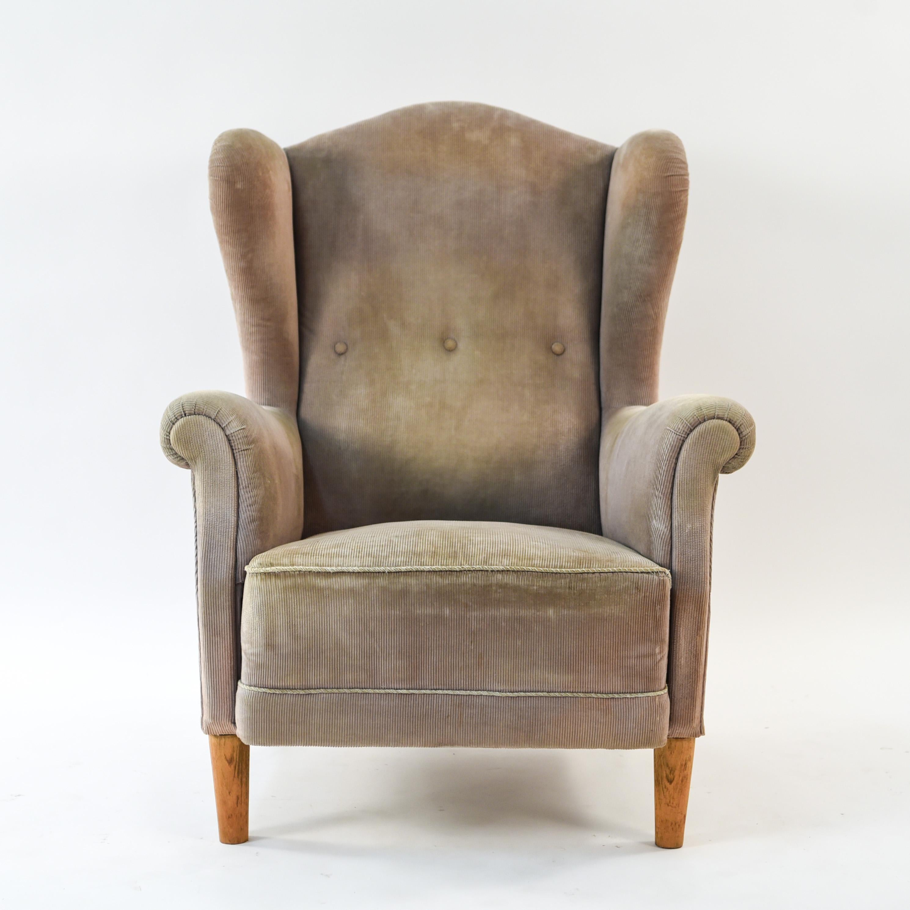 This Danish midcentury wingback chair features three button tufts on the back and scroll form arms. By Peter Hvidt and Hans Wegner.