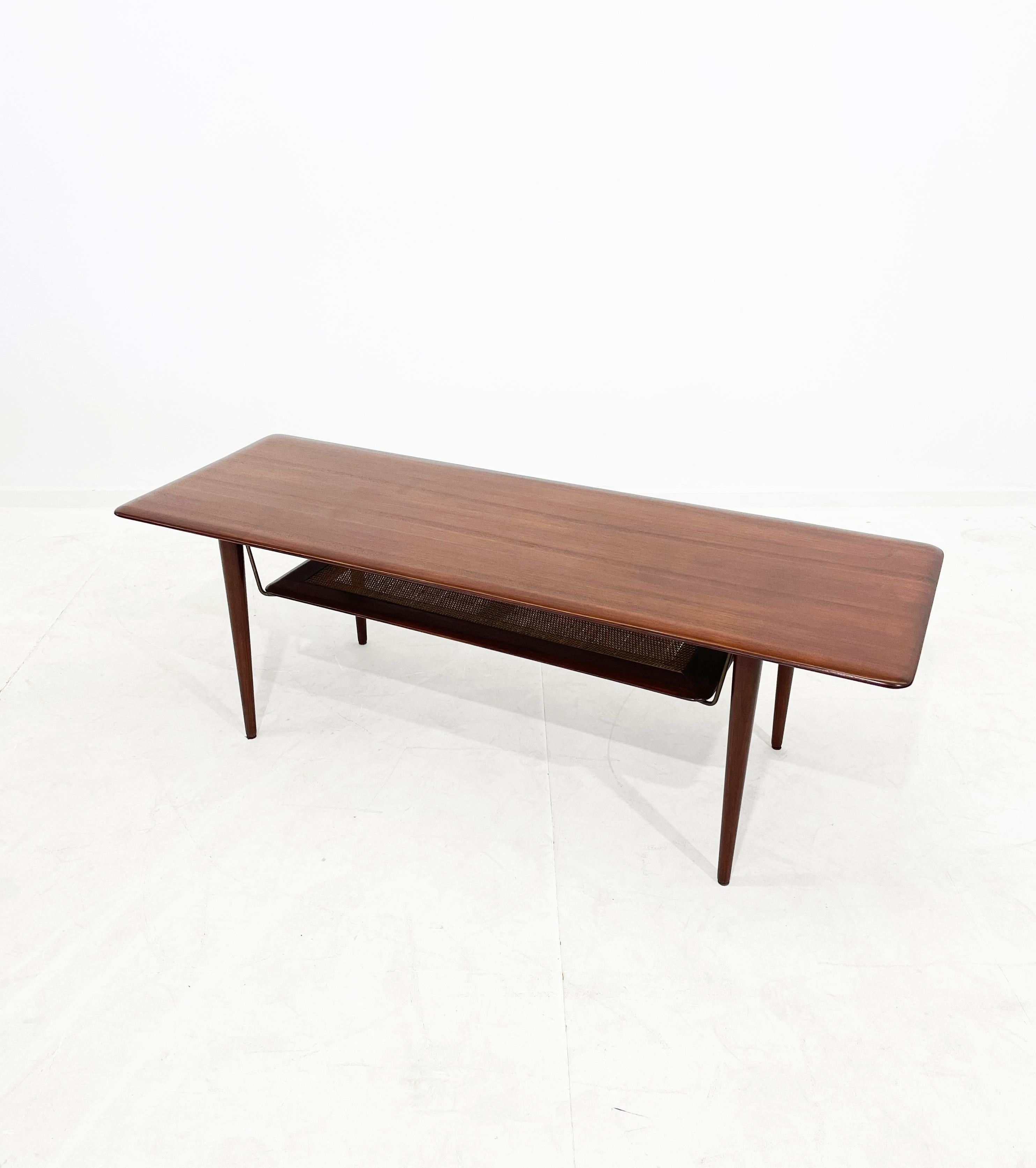 Classic coffee table from the 1960s by Peter Hvidt & Orla Mølgaard-Nielsen for France & Daverkosen. Rare model FD- 516. Frame and table top made of solid teak with an additional shelf made of rattan wicker supported by brass fittings.

The table is