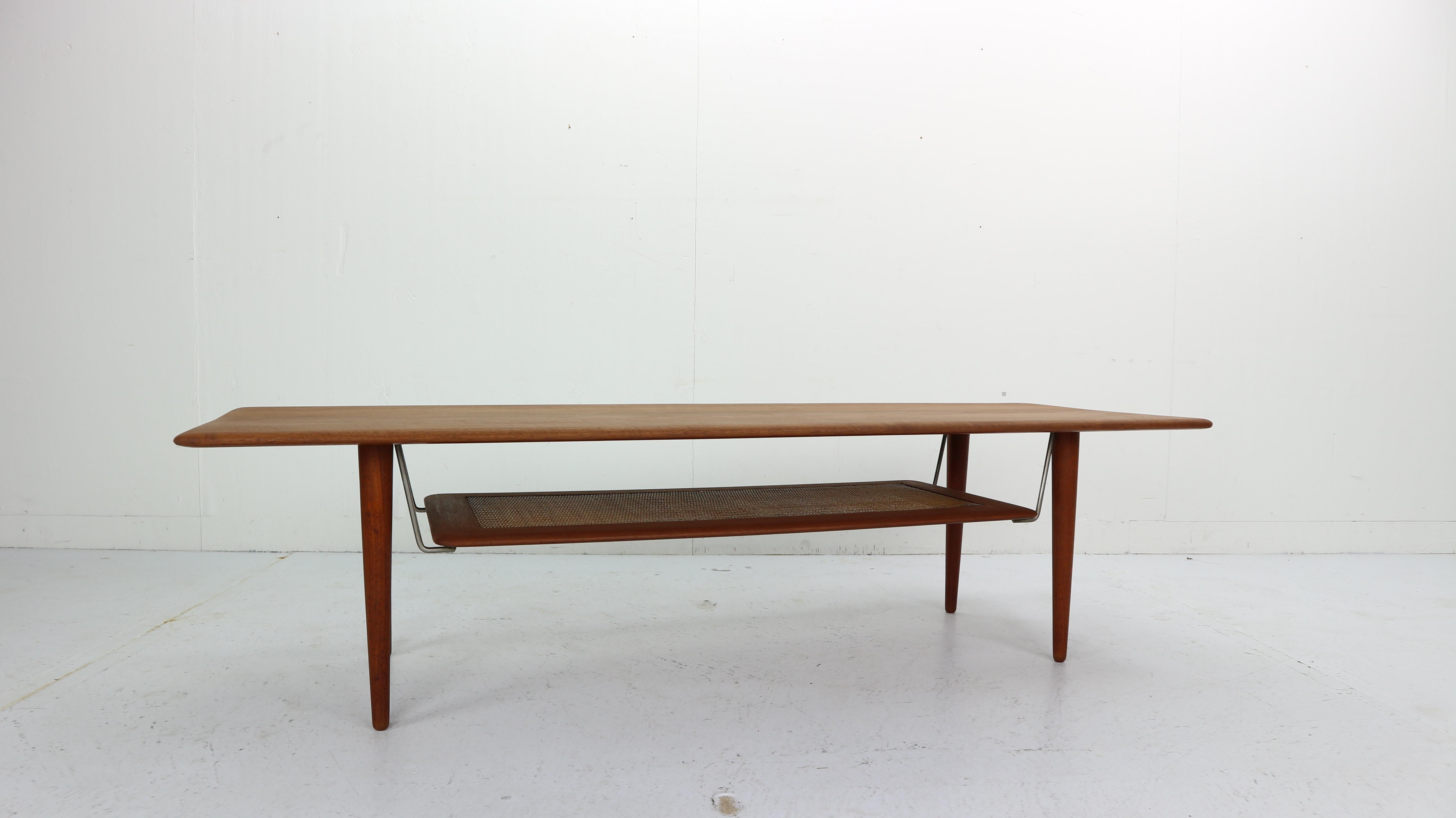 Model FD516 coffee table designed in 1956 by Peter Hvidt and Orla Mølgaard Nielsen for France and Daverkosen. Composed of a solid teak top / legs with a lower cane rack / shelf suspended by polished brass brackets. The solid teak top and tapered