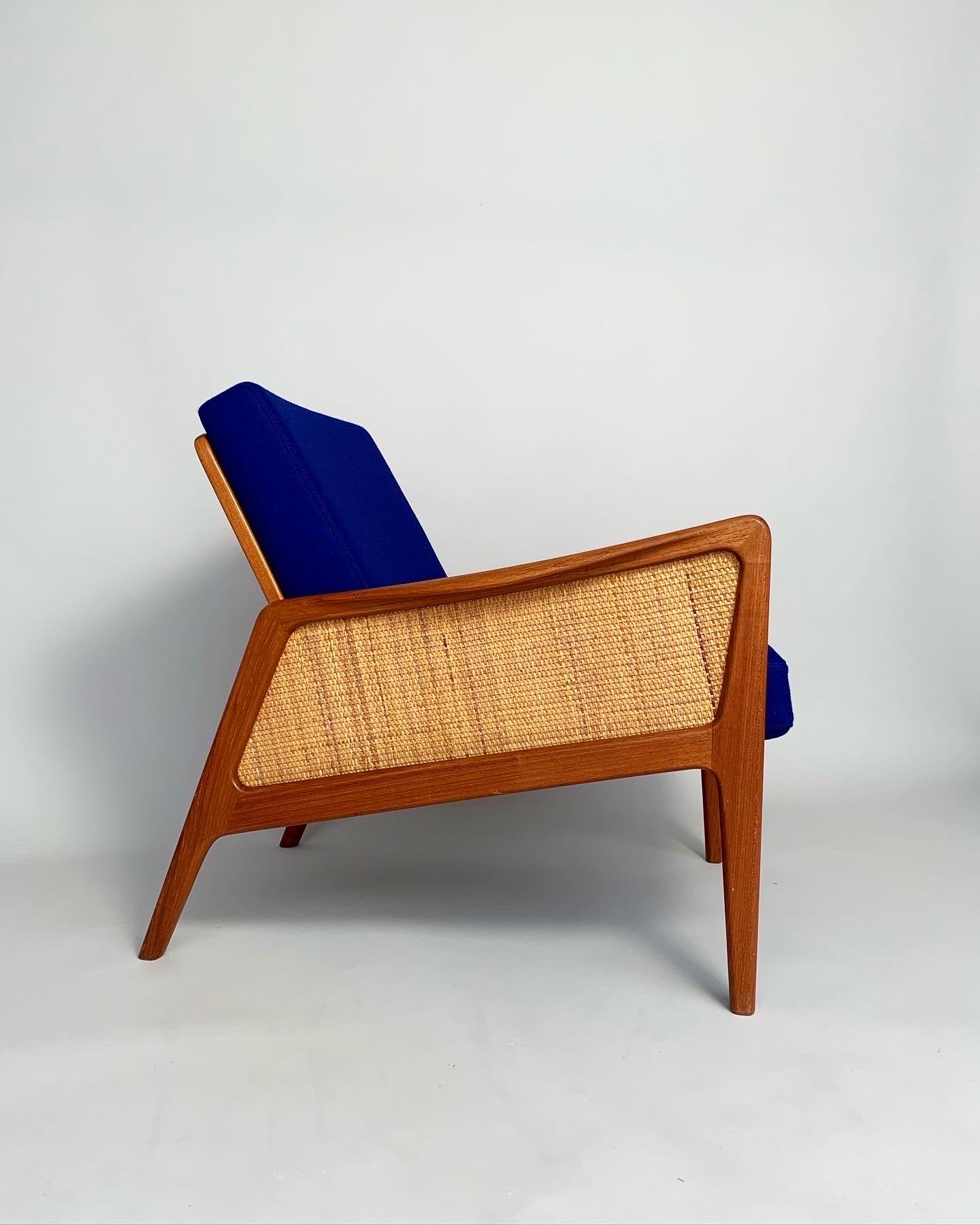 Rare lounge chair by Peter Hvidt & Orla Mølgaard-Nielsen, model FD 151 for France & Daverkosen in the 1950s.

Hand-crafted teak frame with woven cane sides and back, new cold foam cushions covered in dark blue Kvadrat, Divina, No 791. Soft touch and