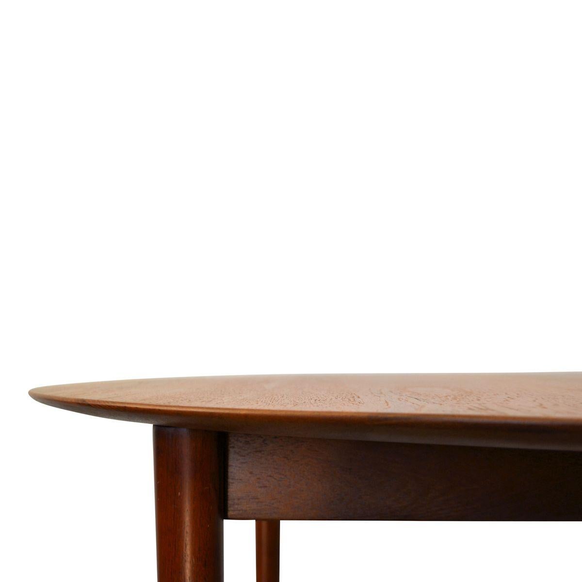 This vintage solid teak dining table, model 311, was designed by Peter Hvidt & Orla Mølgaard-Nielsen for Danish manufacturer Søborg Møbler. This Mid-Century Modern table extended by inserting the extra middle leaf into the elliptic shaped table top.