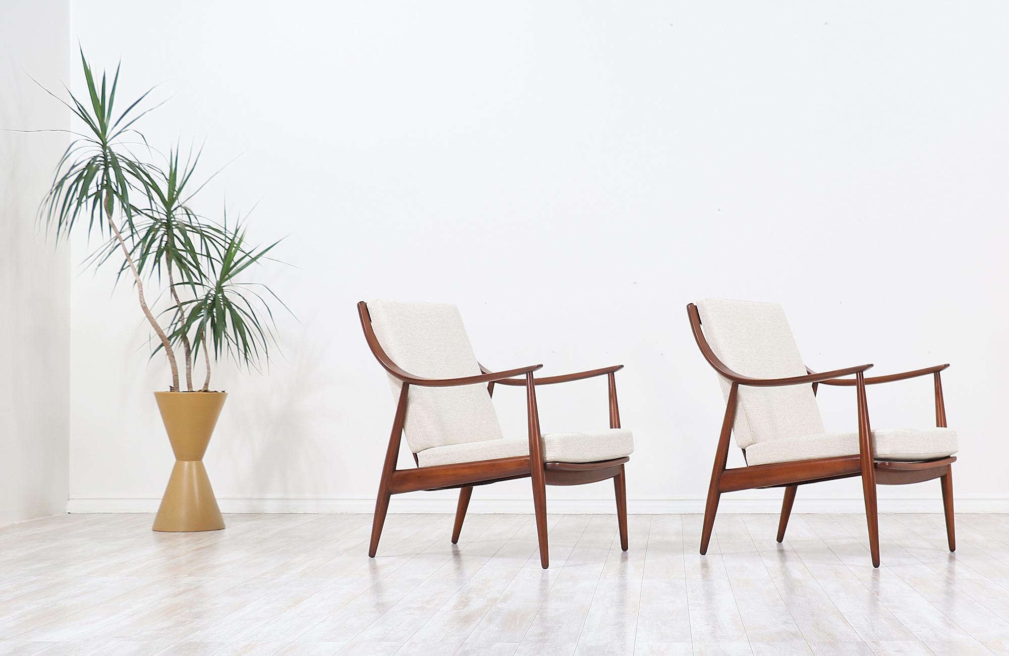 Pair of lounge chairs designed by Peter Hvidt & Orla Mølgaard-Nielsen for France & Daverkosen in Denmark in 1953. This pair of iconic model FD-146 chairs feature a walnut-stained beechwood frame with new high-density foam and cushion tweed