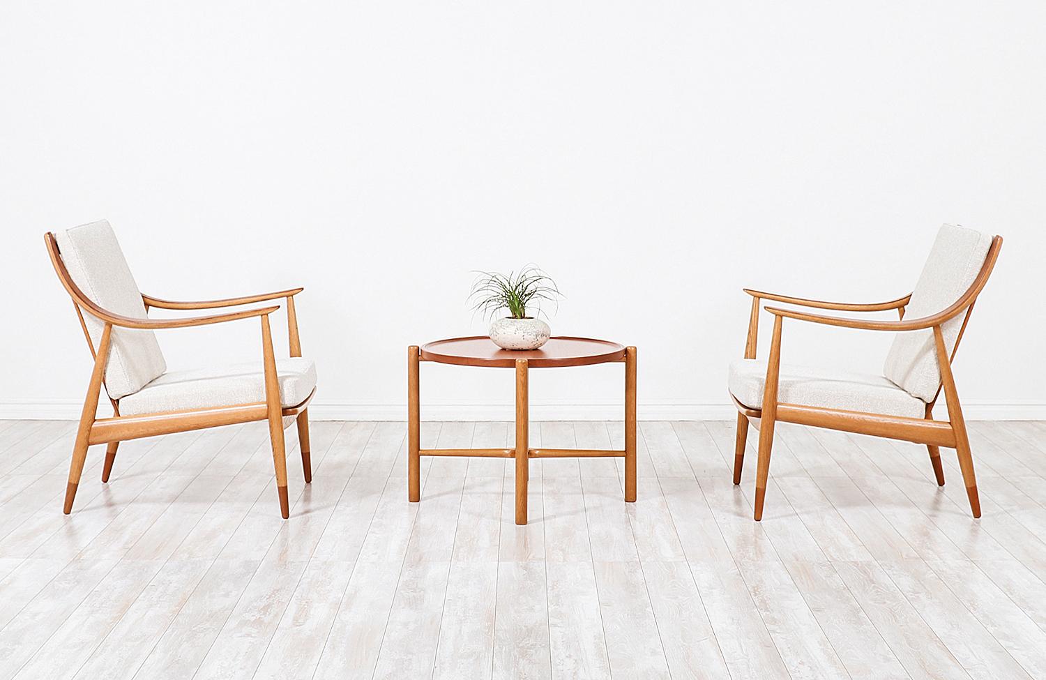 A pair of modern lounge chairs designed by Peter Hvidt & Orla Mølgaard-Nielsen for France & Daverkosen in Denmark, circa 1950s. These stunning model FD-146 chairs feature an angled solid oakwood frame with contrasting darker teak wood sabots and on