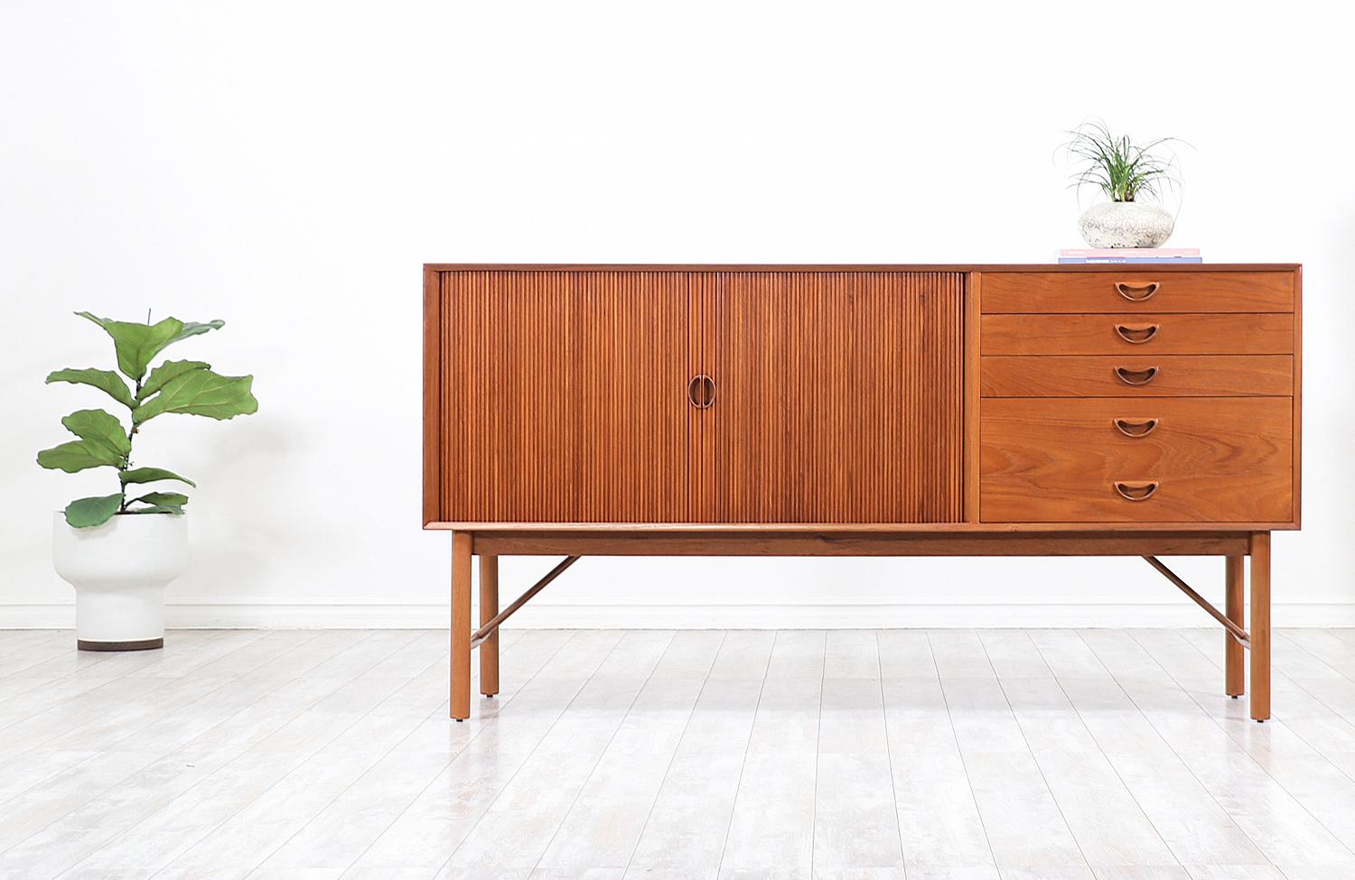 Beautiful Danish modern credenza designed by the iconic Danish duo, Peter Hvidt and Orla Mølgaard Nielsen for Søborg Møbelfabrik in Denmark, circa 1950s. This stylish asymmetrical credenza features a solid teak wood case with finger joints, four