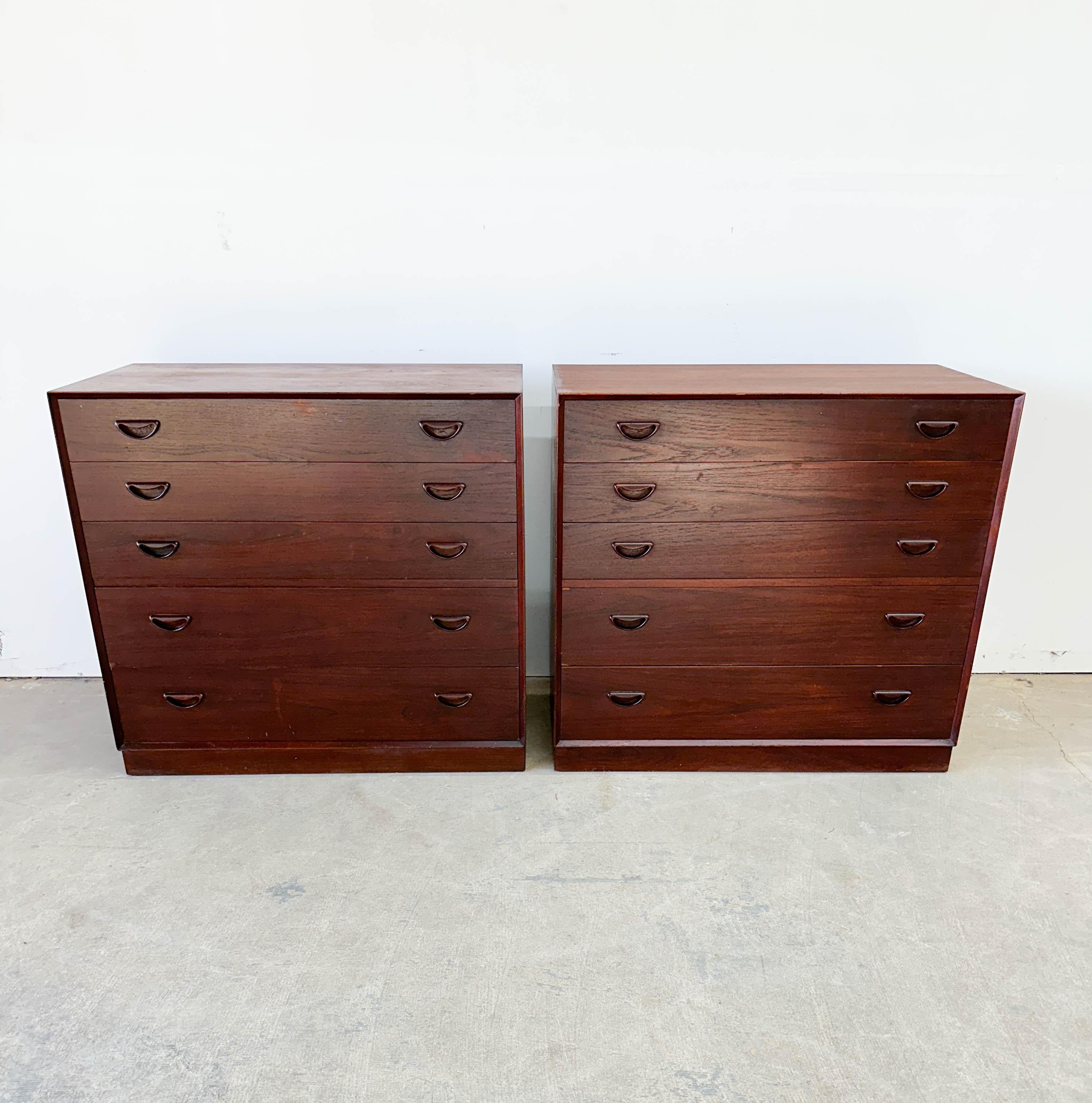 Ricercatissima coppia di comò a cinque cassetti in teak massiccio disegnati da Peter Hvidt e Orla Molgaard Nielsen per France and Son negli anni Cinquanta. Caratterizzati dai caratteristici cassetti a forma di sorriso e dalle casse con giunture a