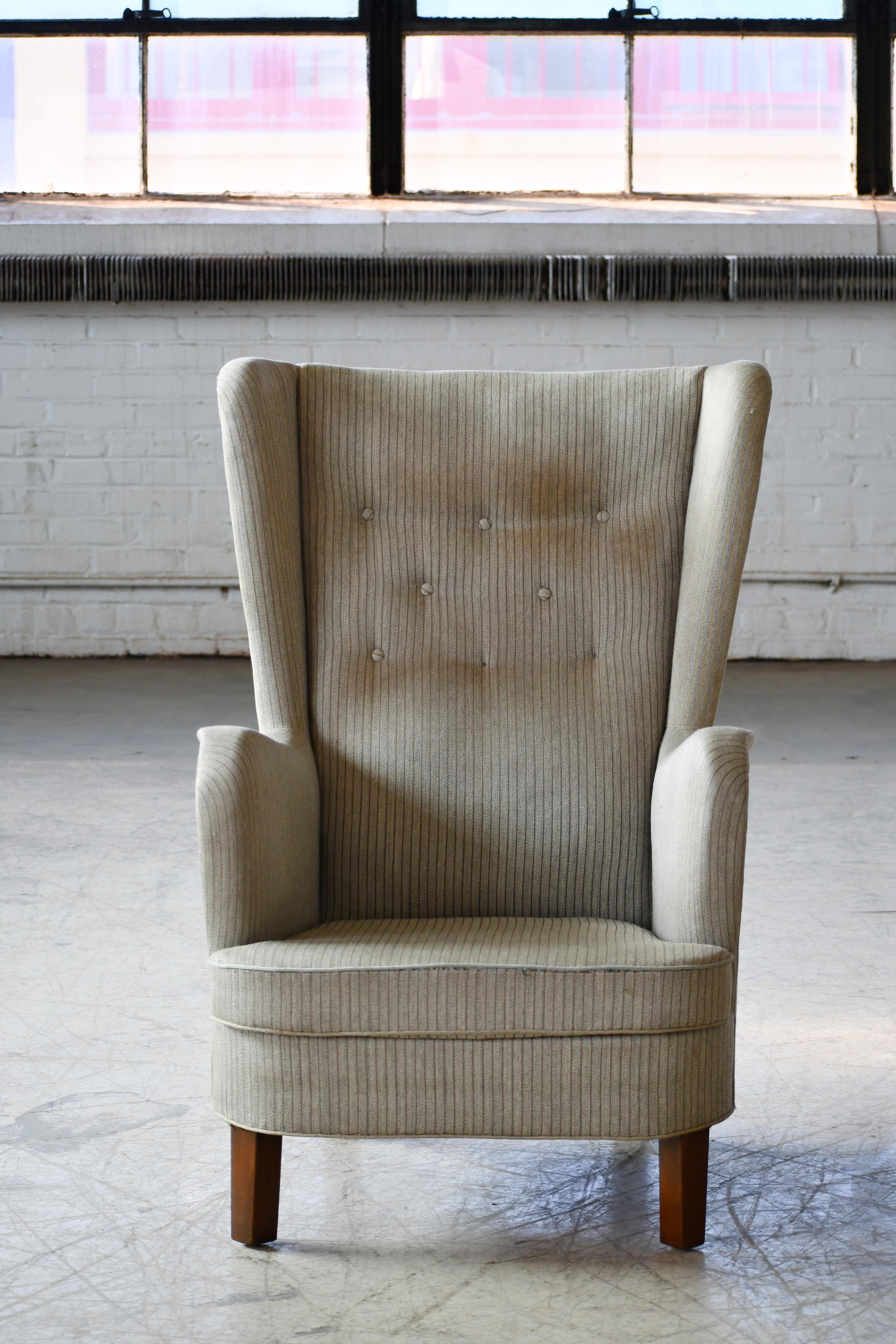 Great Danish 1950s high back armchair in the style of Peter Hvidt and his typical designs. We love the stylistically strong and simple yet refined lines. Tall slim silhouette raised on beech wood legs. The fabric is is showing wear and dirt and we