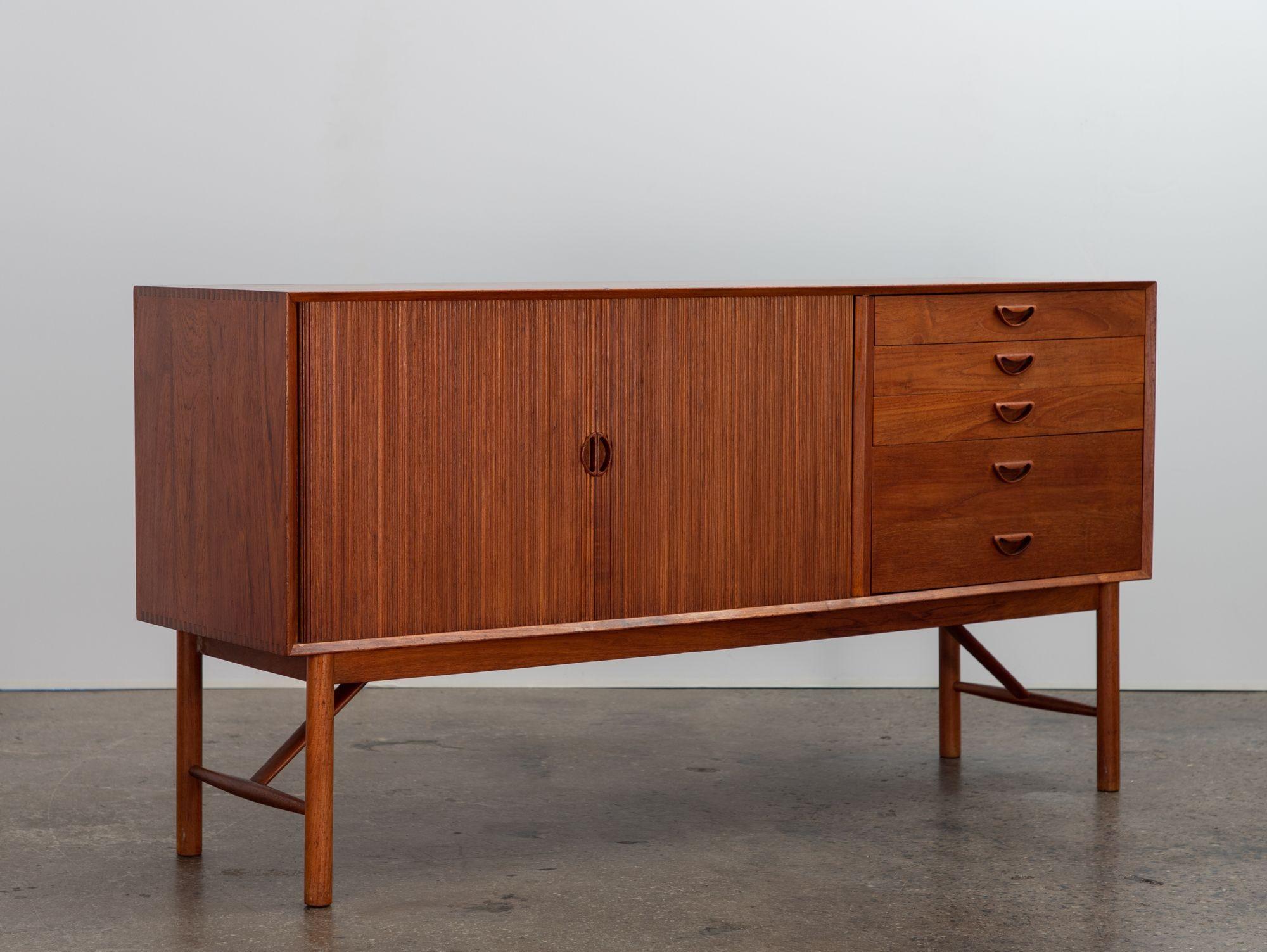 Danish modern tambour credenza, designed by Peter Hvidt and Orla Mølgaard-Nielsen for Søborg. Cabinet features carved handles and signature finger-joint cabinet details. Tambour door slides smoothly to reveal adjustable shelves at the interior,