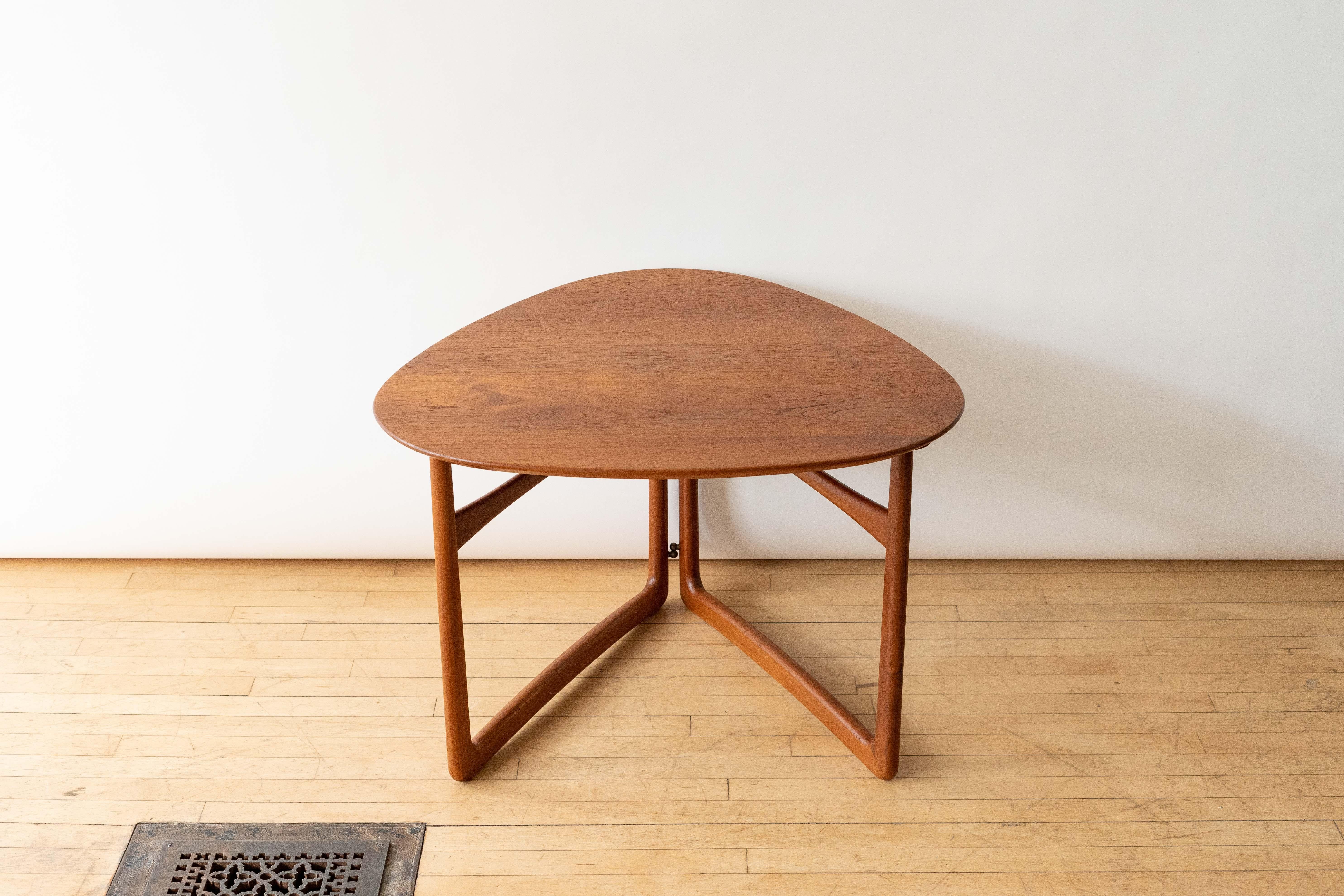 Denmark, ca. 1950s. An early Model 18/57 table by Peter Hvidt and Orla Mølgaard-Nielsen for France & Daverkosen. Features solid teak construction with triangular beveled top supported by softly rounded legs. Clever folding design with subtle brass