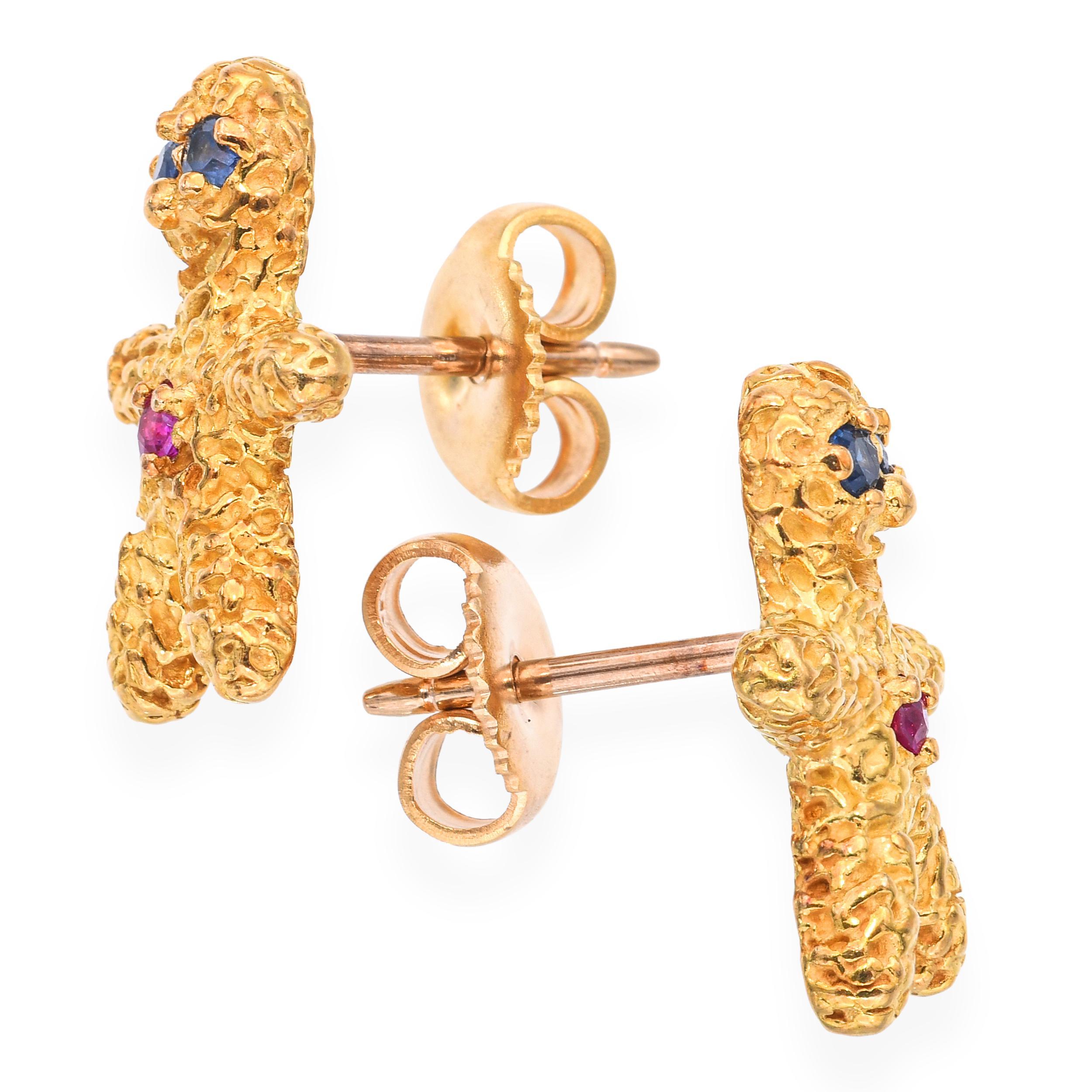 Diese skurrilen Vintage-Ohrringe von Peter Lindeman sind aus 18 Karat Gelbgold gefertigt und als charmante Miniatur-Lebkuchenfiguren gestaltet. Die Figuren sind mit leuchtenden Rubinen und Saphiren verziert, die für spielerische Farbakzente und