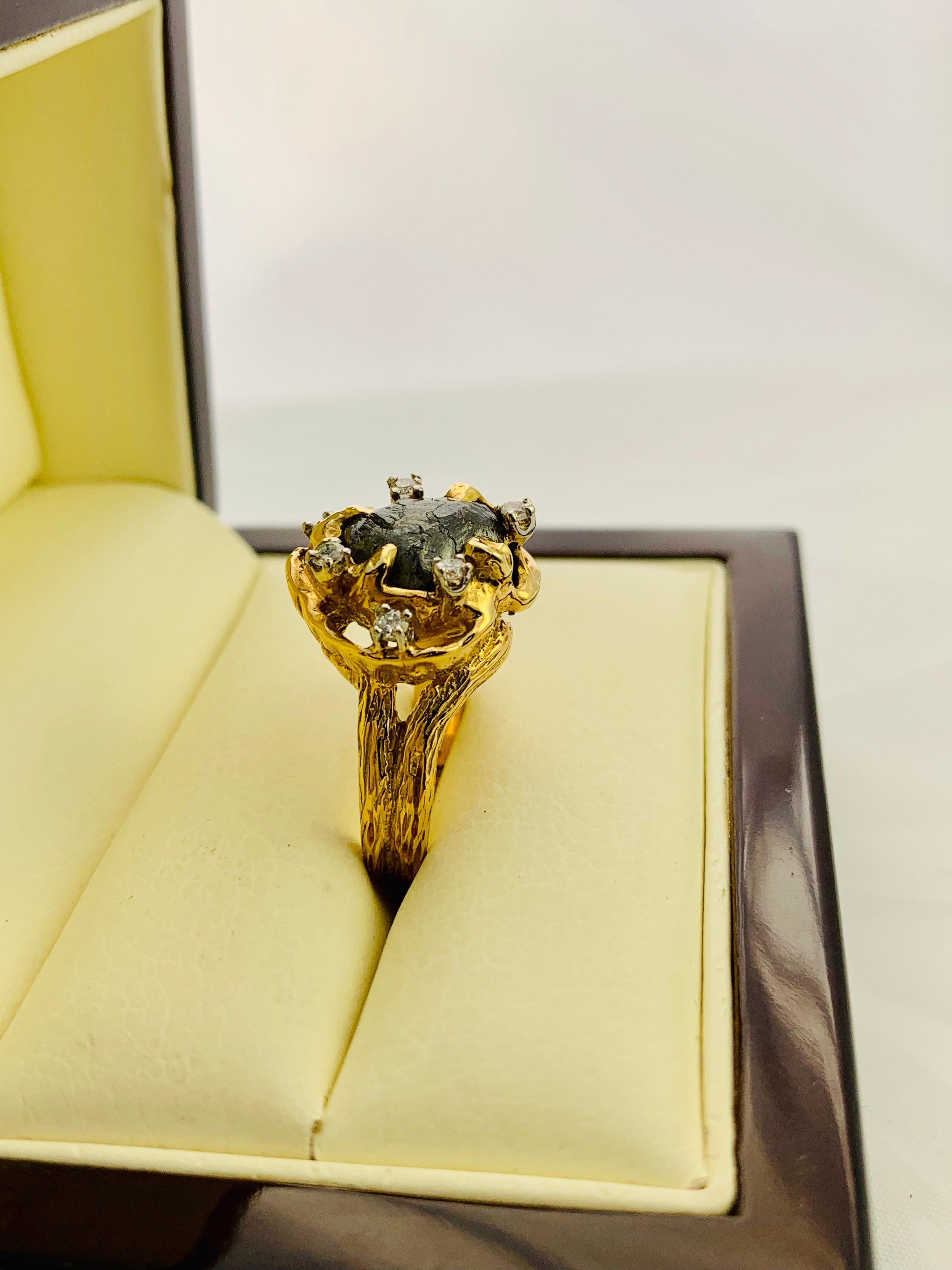 Gorgeous and such a Unique, Modernist Piece to add to your Collection! Designed by Peter Linderman, this piece has an 18K Yellow Gold, Bark Designed mounting that features a single, natural rough cut diamond that is surrounded by 7 round diamonds.
