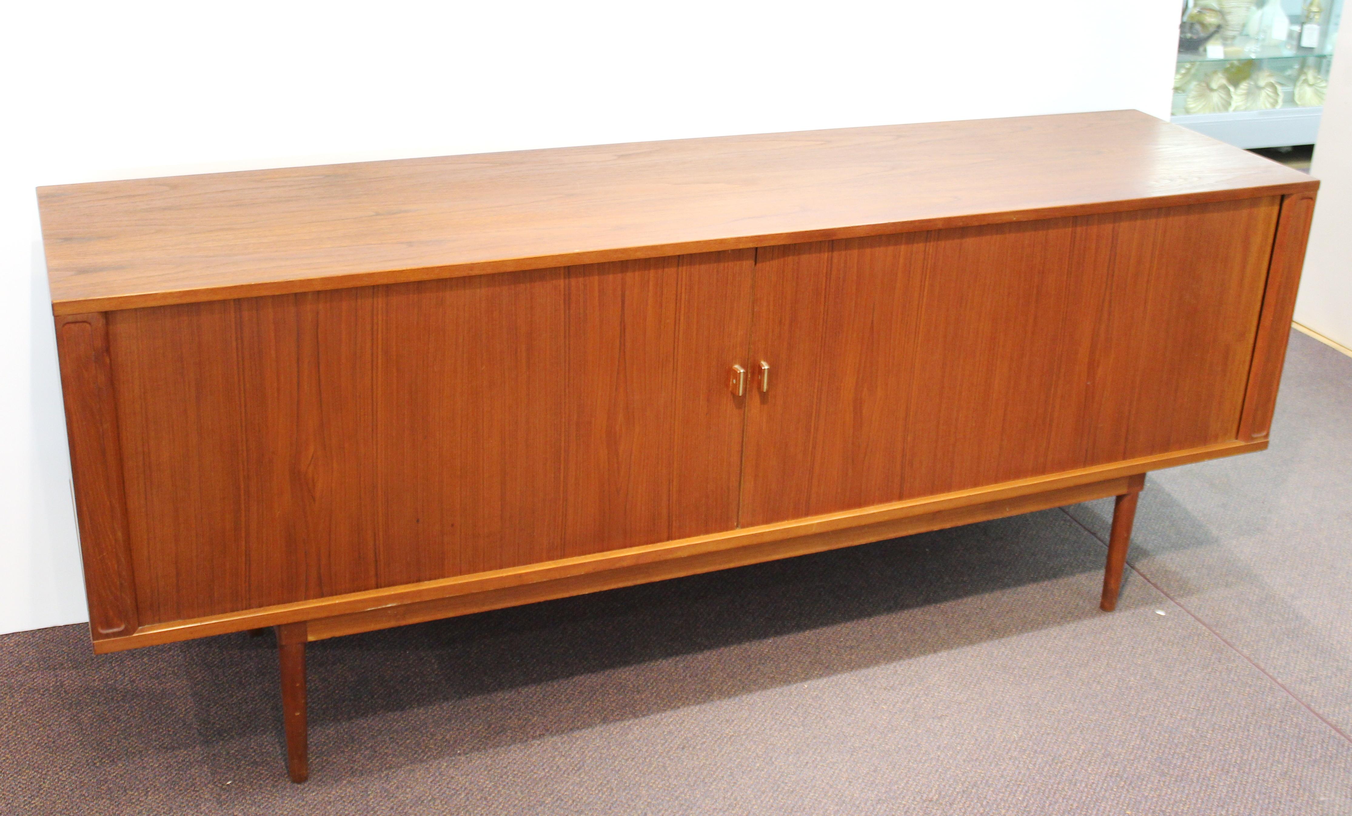 Danish modern credenza designed by Peter Løvig Nielsen in the 1960s. The piece has two tambour doors that slide open to reveal two compartments with storage shelving and one central compartment with flat tray drawers. The pulls have metal accents.
