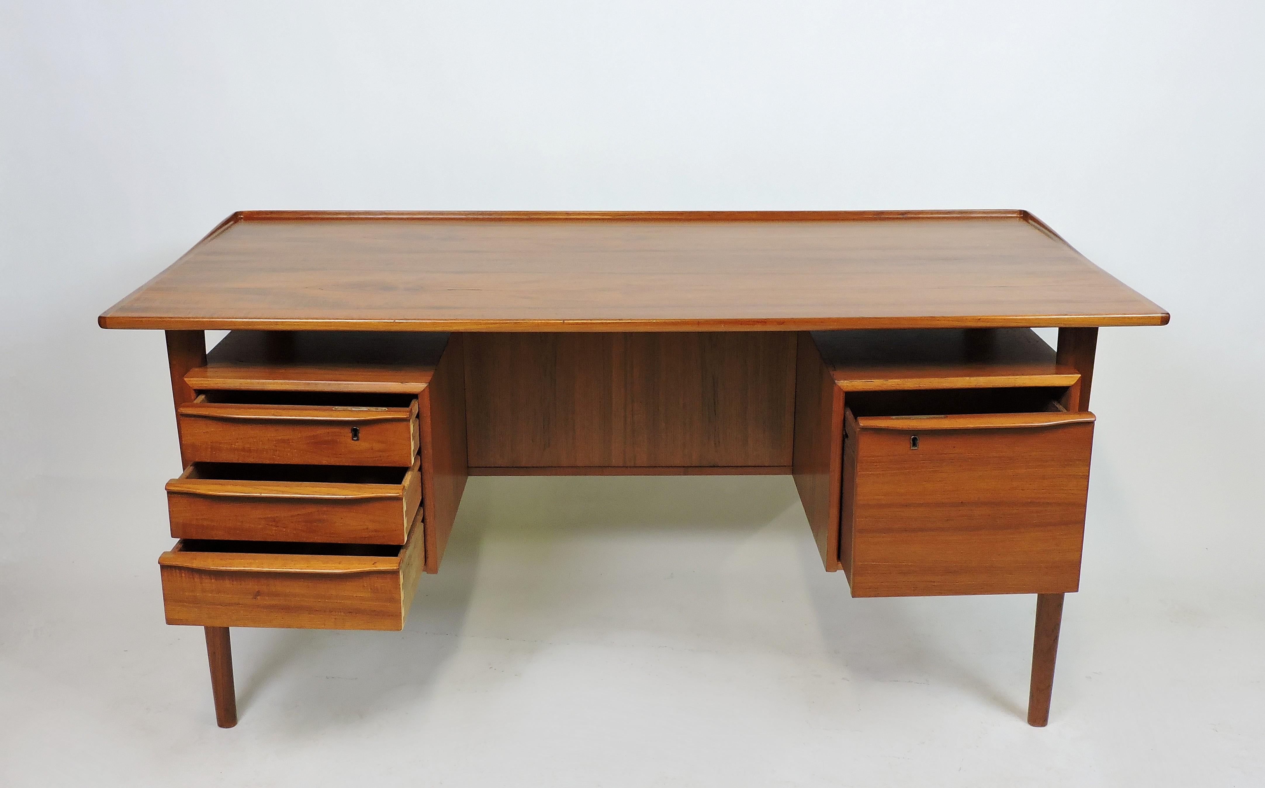 Handsome freestanding teak desk designed by Peter Løvig Nielsen and made in Denmark. This desk has a generously sized floating top, three drawers including one that locks, a file cabinet that also locks, and two storage compartments with a shelf in