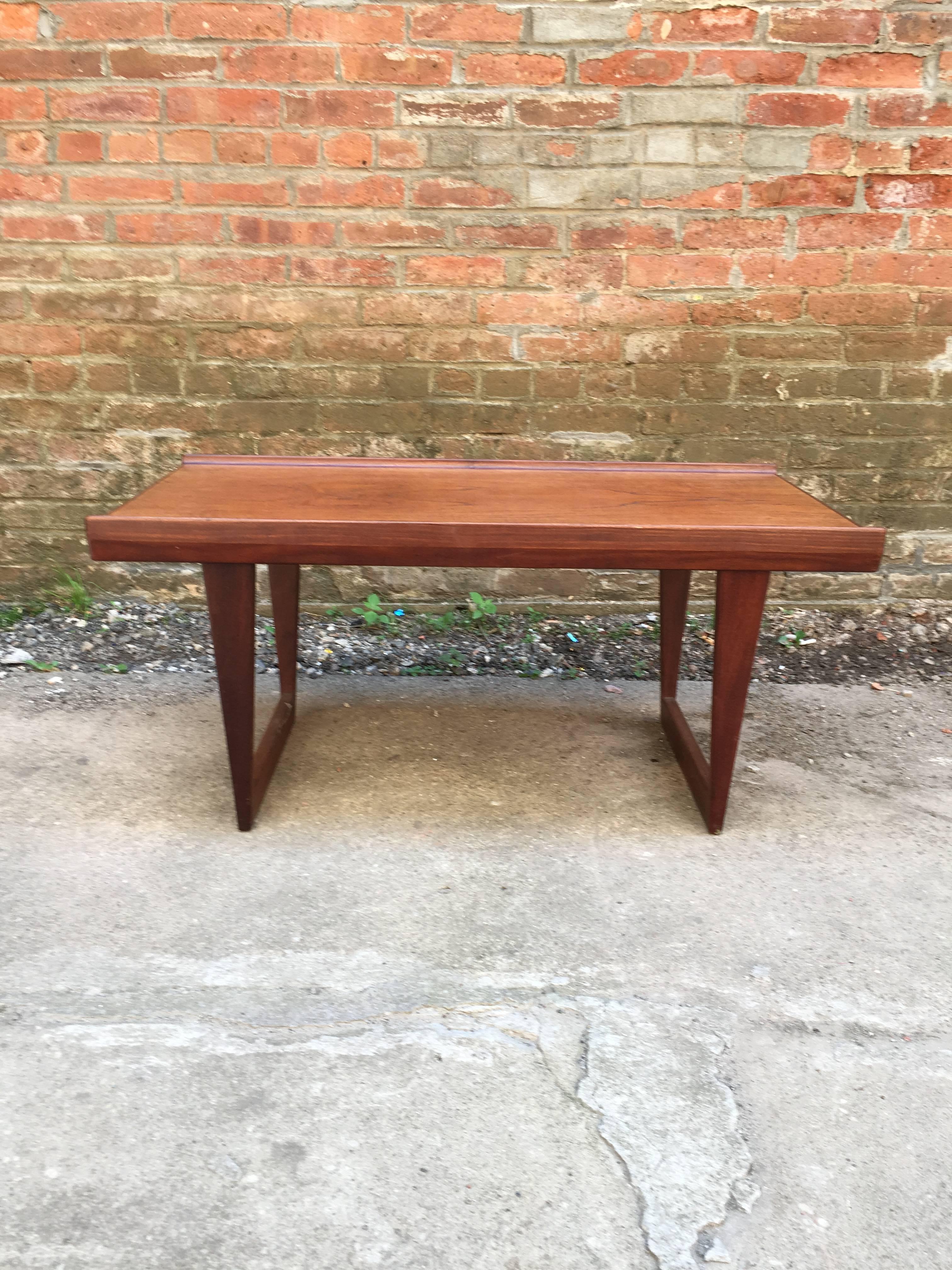 Excellent compact teak coffee table designed by Peter Loving Neilsen, Dansk Designs, Denmark. Solid teak legs and channeled sides. Fully signed with burn in mark on the bottom. Good original finish.
