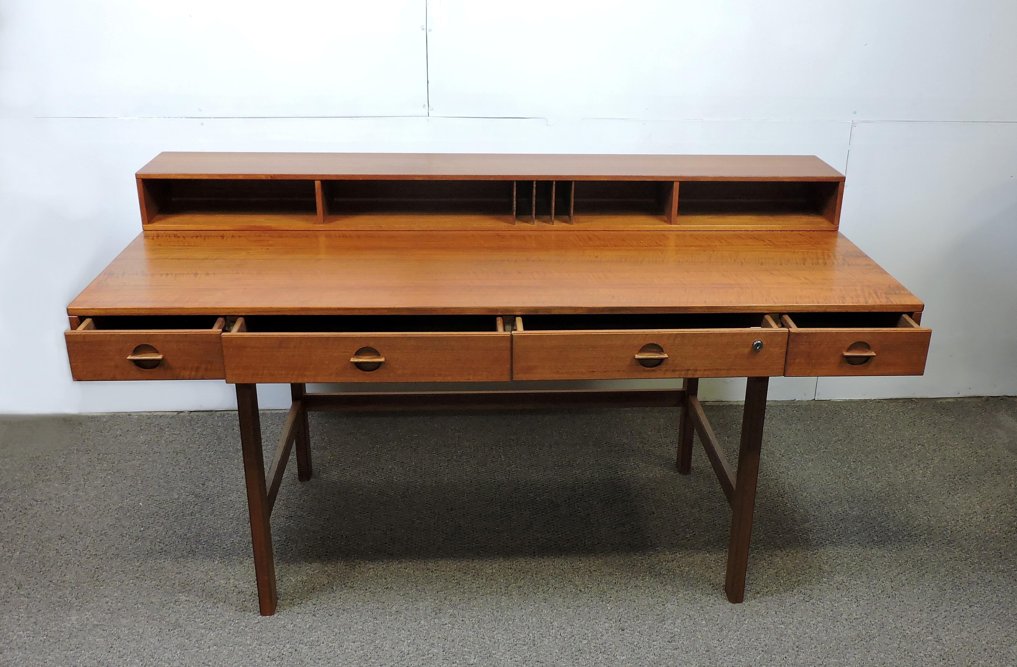 Handsome teak partners desk designed by Peter Lovig Nielsen and made in Denmark. This desk has four drawers and a large work space with cubbyholes that can be flipped back on brass hinges to make an even larger (38