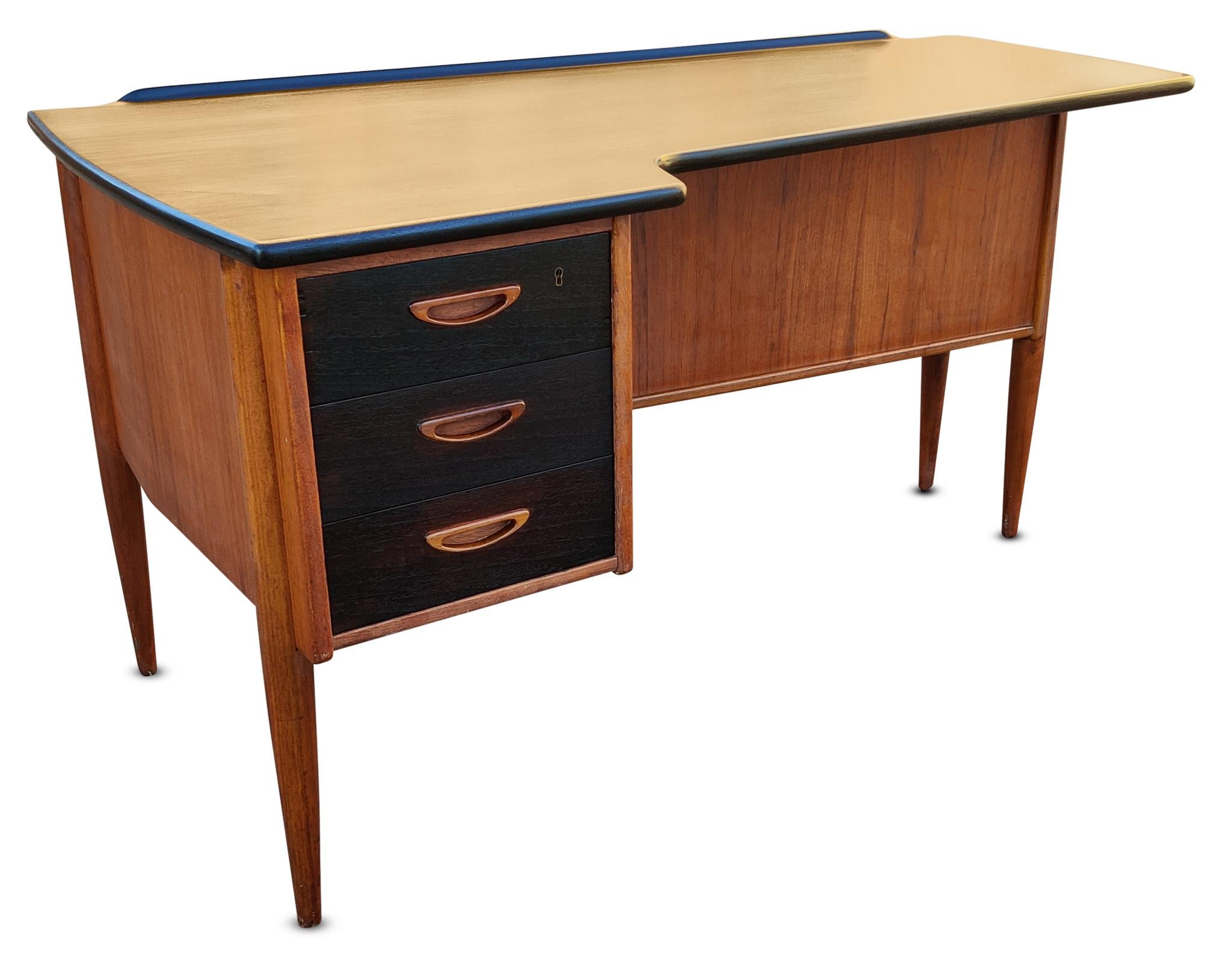 Desk, Denmark, circa 1960s. Designed by Peter Lovig Nielsen, this model is known as the Boomerang Desk because of its slightly curved top. Our model is constructed of oiled teak with Jacobian stained top and drawerfronts. Notice the carved and inset