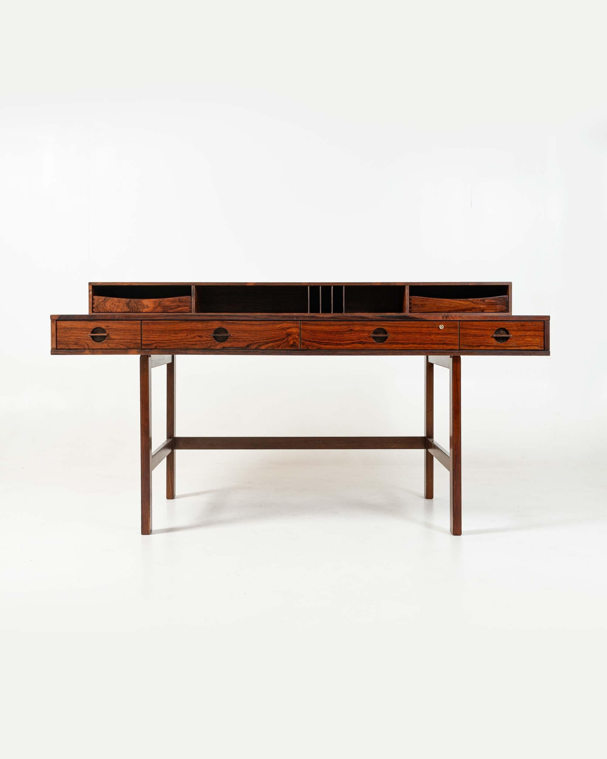 Rarissima scrivania per partner con piano a ribalta di Peter Lovig Nielsen in palissandro con finiture in ottone. Conserva i vassoi originali per gli armadietti del livello superiore. Il ripiano superiore della scrivania si ribalta per ampliare la
