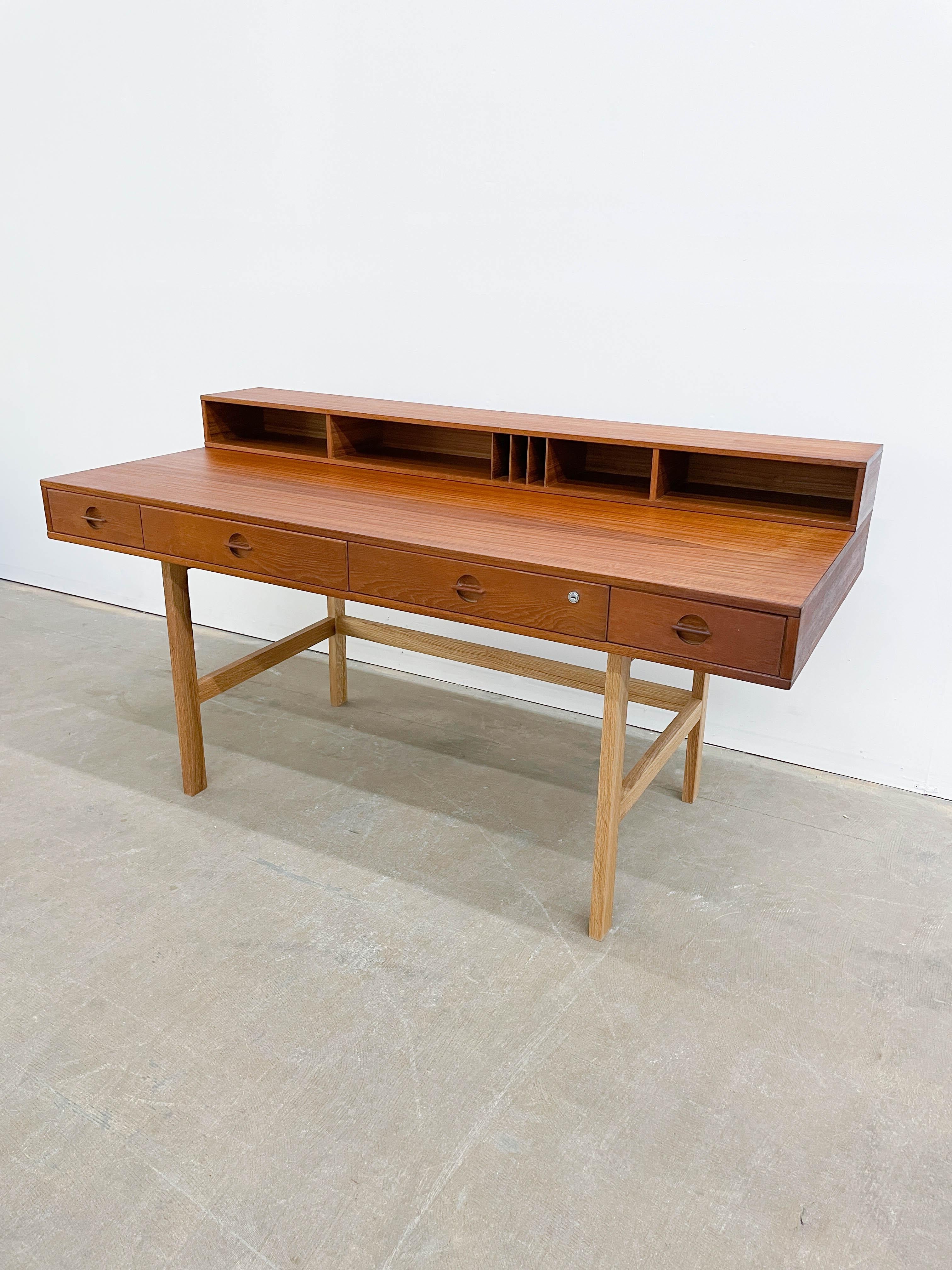 This is a stylish 1970s Danish Modern Teak flip-top desk by Peter Lovig Nielsen. Angular and architectural, this generous desk offers excellent storage in the four front drawers and seven top cubbies in varied sizes. It also transforms with the