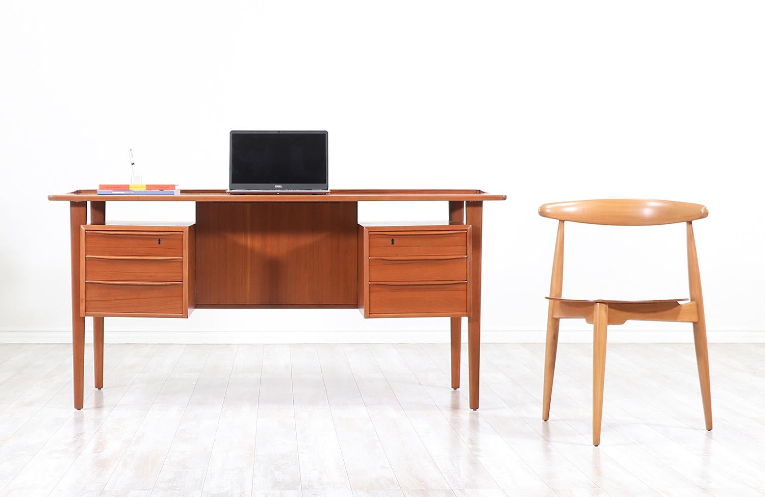 Elegant modern executive desk designed and manufactured by Peter Løvig Nielsen in Denmark, circa 1970s. This stunning freestanding teak wood desk features sturdy construction with three drawers on each side and a fully finished open back with a