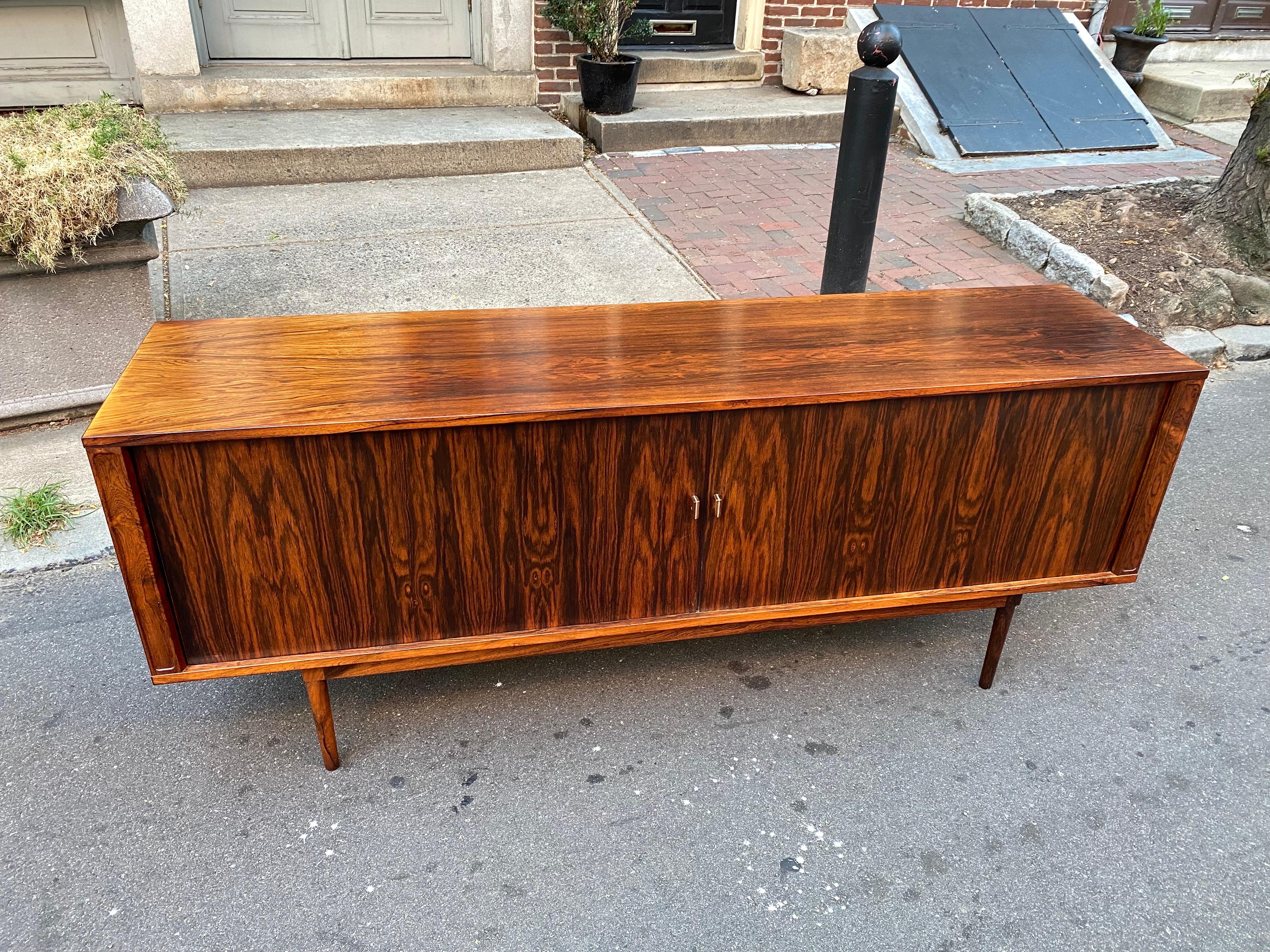 Lovig Rosewood Tambour door credenza. Doors open to reveal 5 shallow pull out drawers in the center, top 2 with felt, Each side has an adjustable shelf, not seen in photo. Beautifully refinished and ready to go! Truely amazing rosewood grain