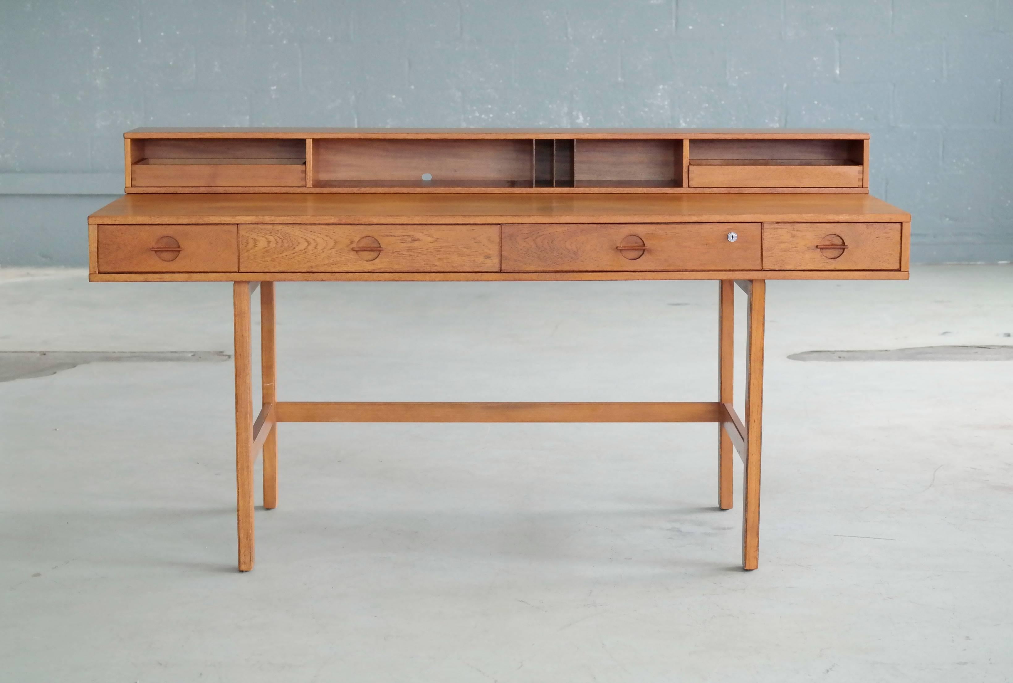 Beautiful 1960s teak desk by Peter Lovig Nielsen and Jens Quistgaard made of solid teak wood and teak veneer with a beautiful wood grain and nice light color, finished with solid brass hinges. The sleek, angular and functional design is very