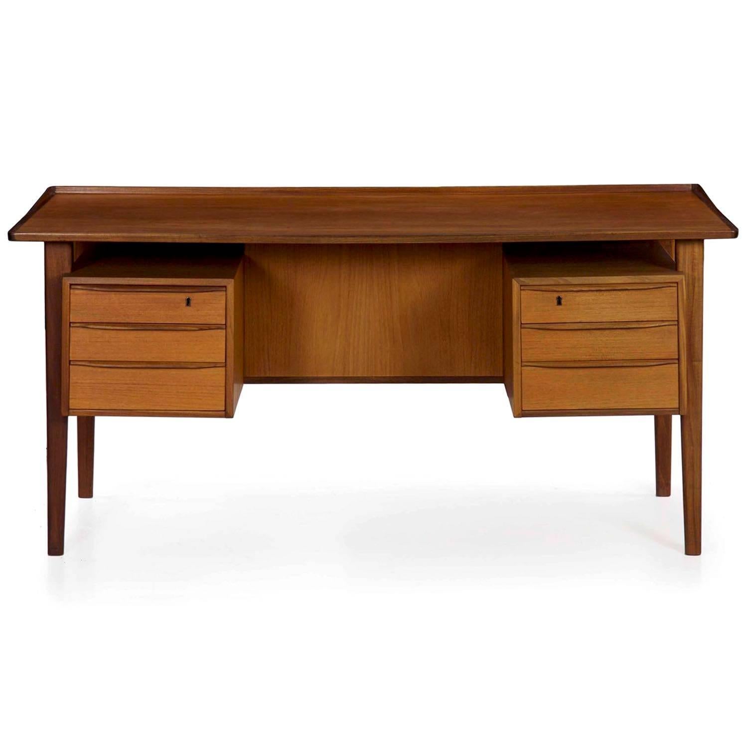 An exceptional sculpted teak desk by Peter Løvig Nielsen for Dansk Design of Denmark, it is notable for the sculpted floating writing top with its faceted upraised edging. The facets are followed through in the rest of the desk design, allowing the