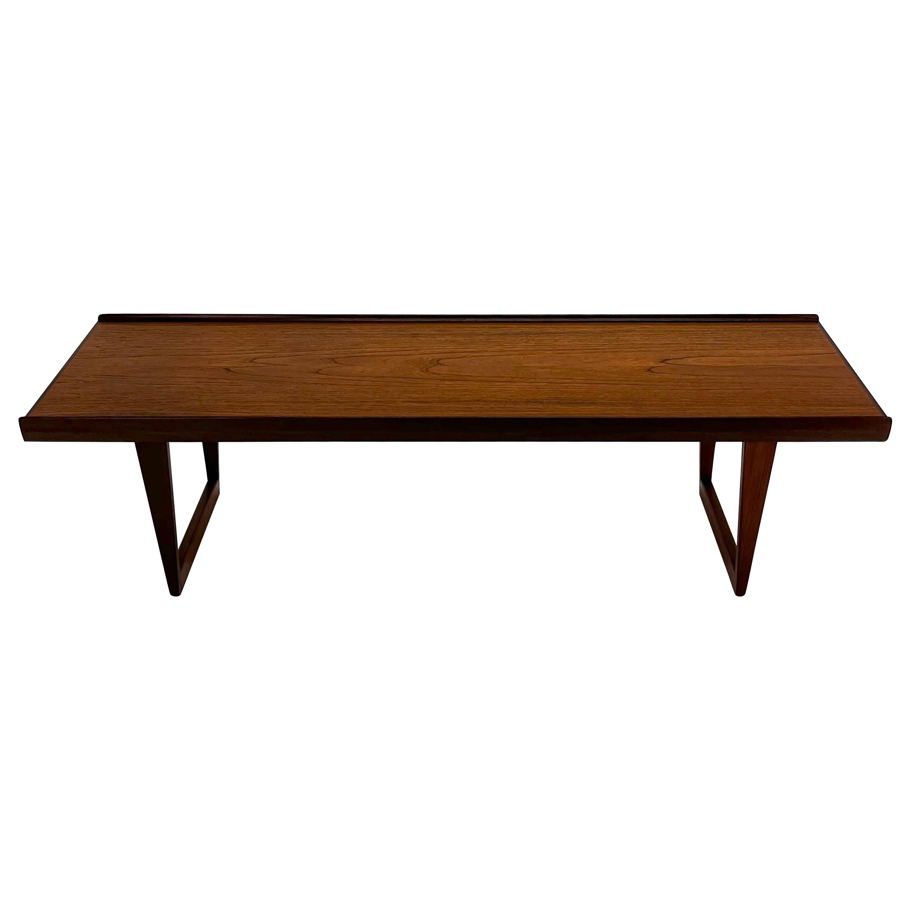 As architecturally fascinating as it is aesthetically pleasing, these iconic tables, designed by Peter Løvig Nielsen in the early 60's. Featuring turned edges built of solid teak with exceptional woodgrains set atop a set of sled legs, this table is