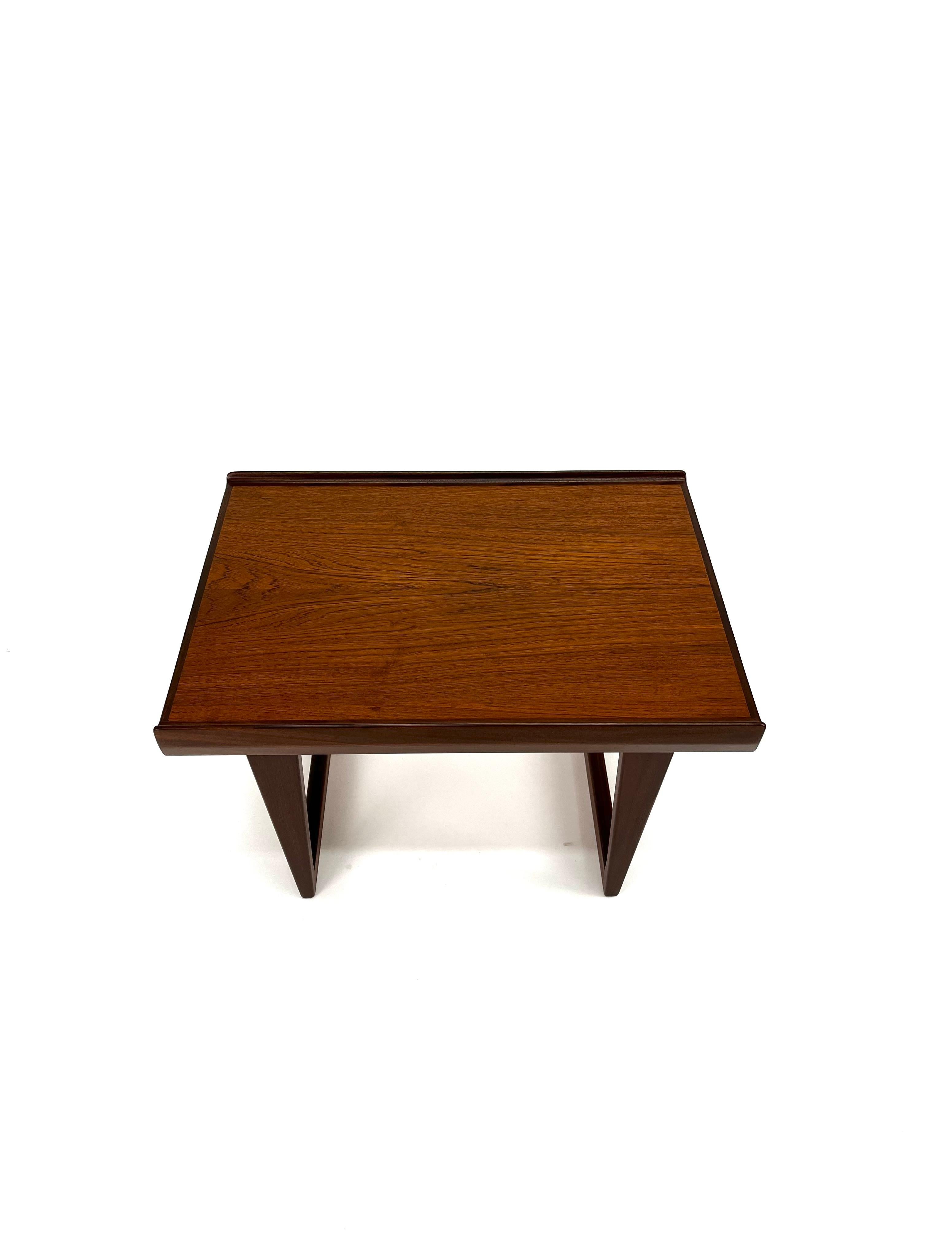 As architecturally fascinating as it is aesthetically pleasing, this iconic table, designed by Peter Løvig Nielsen in the early 60's. Featuring turned edges built of solid teak with exceptional woodgrains set atop a set of sled legs, this side table