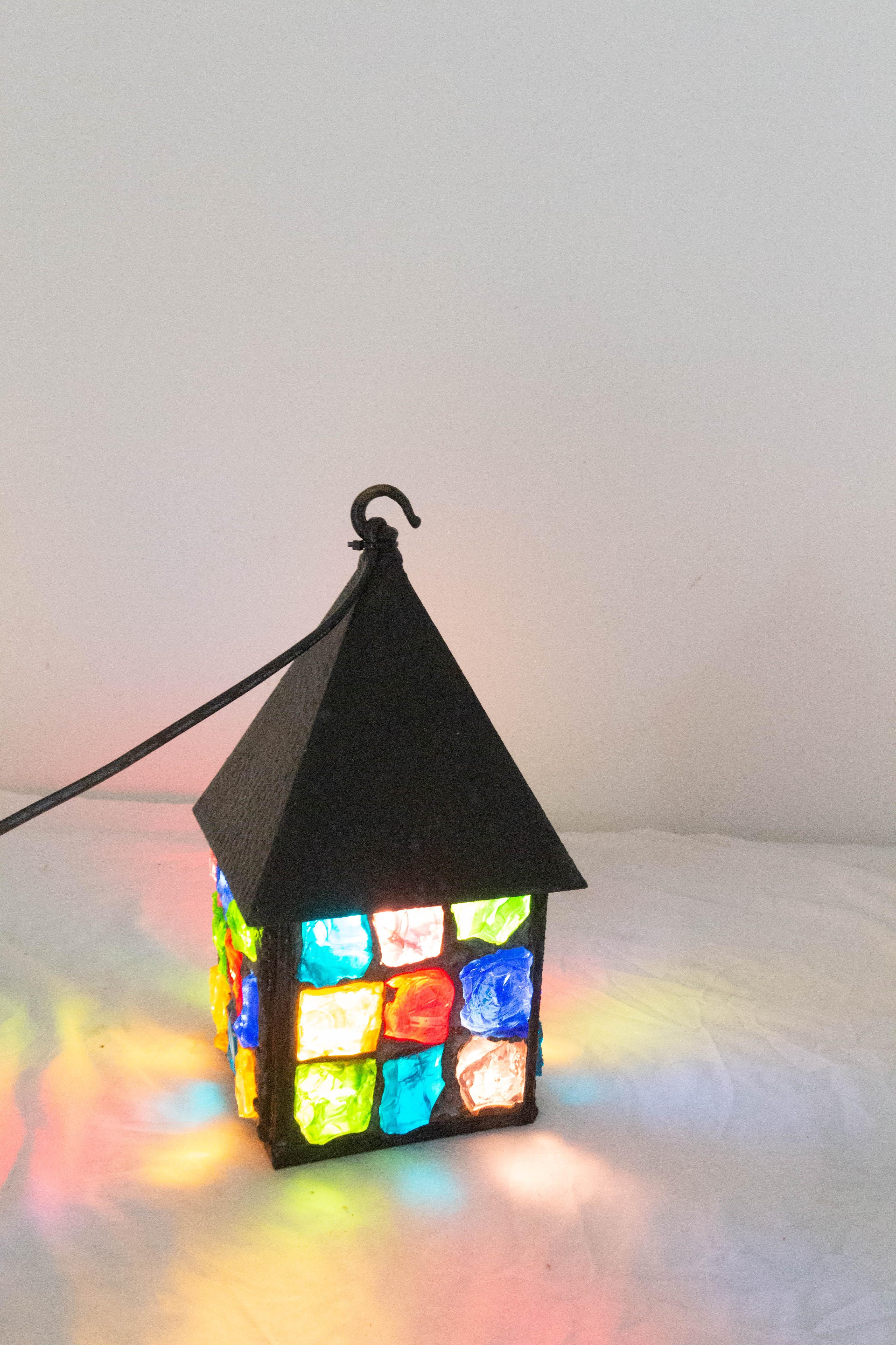 Wrought iron light lantern by Peter Marsh 
English Midcentury
Good vintage condition with good patina
Multicolored glass sealed with lead
It also can be used as a table lamp if you add a switch.
This can be re-wired and tested to USA or