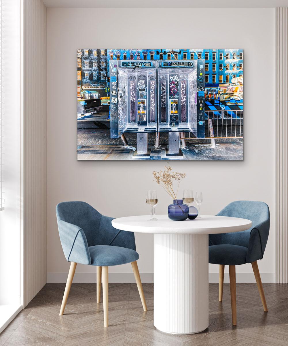 This contemporary photograph by Peter Mendelson is a metal sublimation print. It features a cool palette, and captures two phone booths covered in graffiti writing on a city street lined with large buildings. 

This is a metal sublimation print. The
