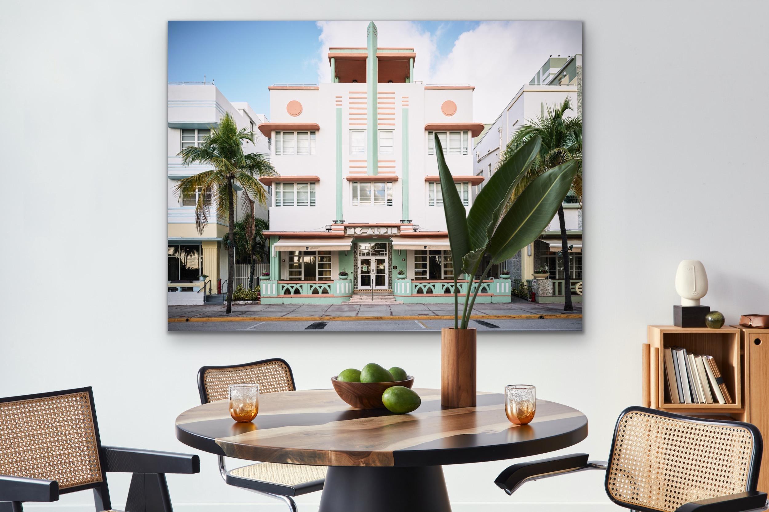This contemporary urban photograph by Peter Mendelson captures the Deco style MC Alpin building in Miami Beach, Florida, with palm trees and neighboring Deco style buildings on either side. 

This is a metal sublimation print. The frame on an