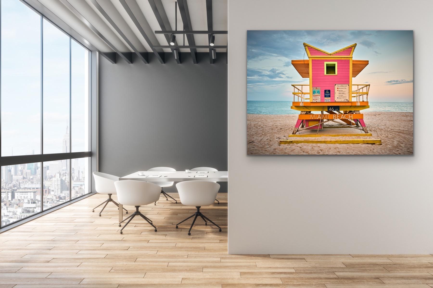 This contemporary coastal photograph by Peter Mendelson features a warm, subtle palette. It captures one of the famously unique lifeguard stands of Miami Beach, Florida, with magenta panelling and yellow and orange trim. The lifeguard stand