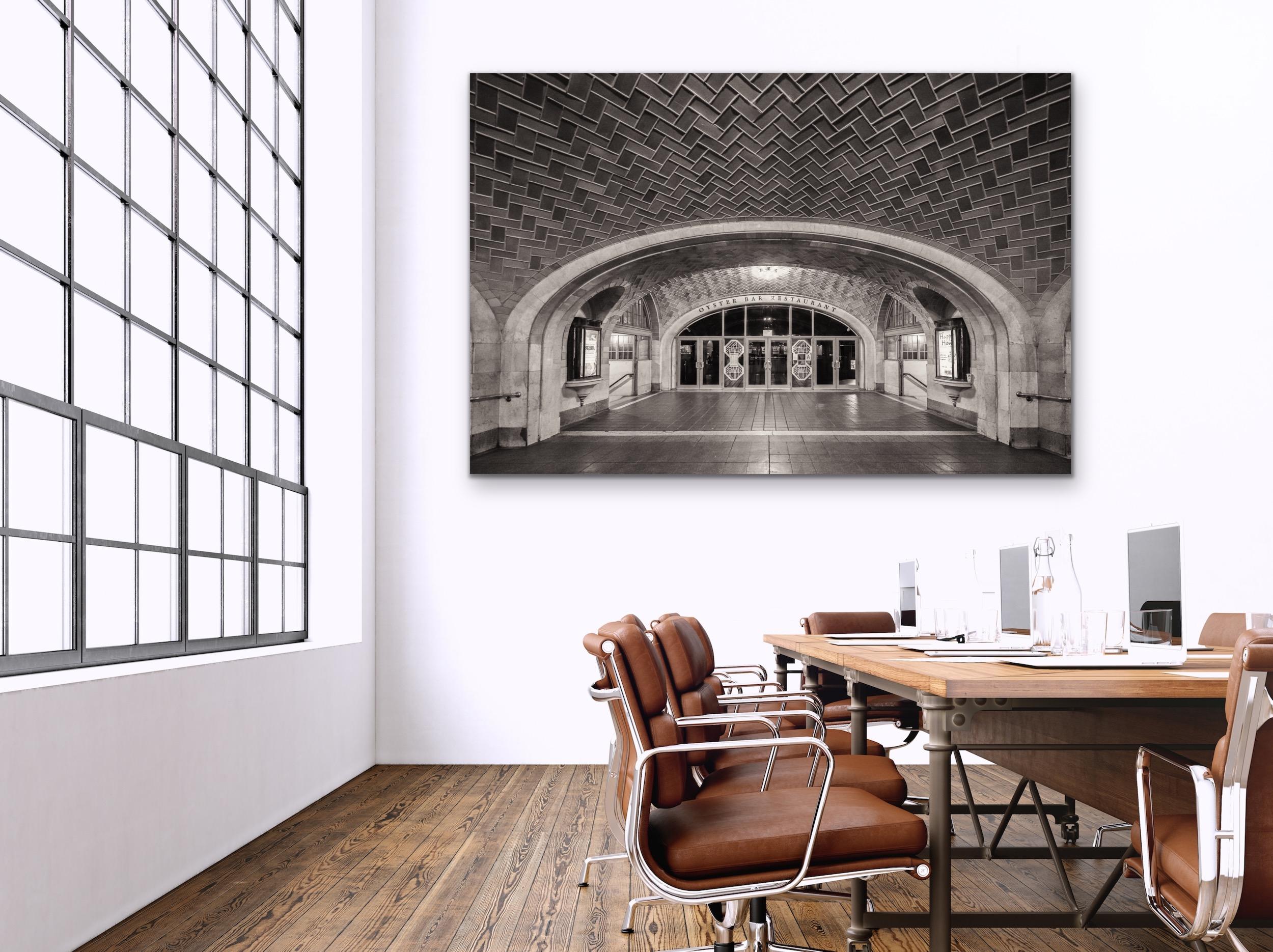This black and white, contemporary architectural photograph by Peter Mendelson features the Oyster Bar Restaurant in Grand Central Station in Manhattan. Two staircases lead to a lower level on either side of the entry to the restaurant, while