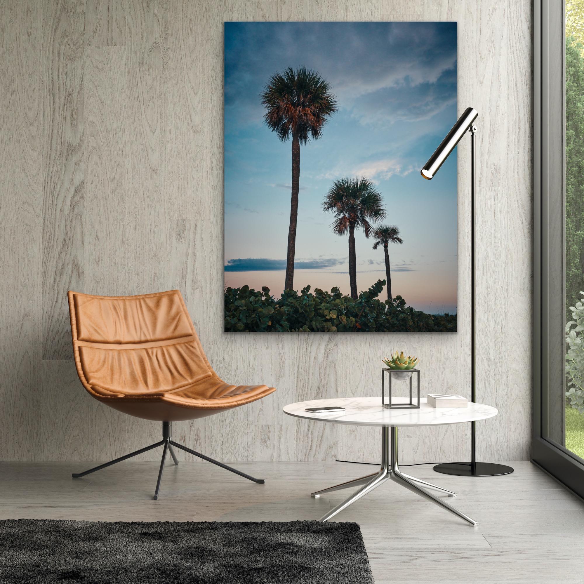 This contemporary coastal photograph by Peter Mendelson features a cool palette, capturing three palm trees beneath a subtle blue sky at sunset on Miami Beach. 

This is a metal sublimation print. The frame on an aluminum print is flush with the