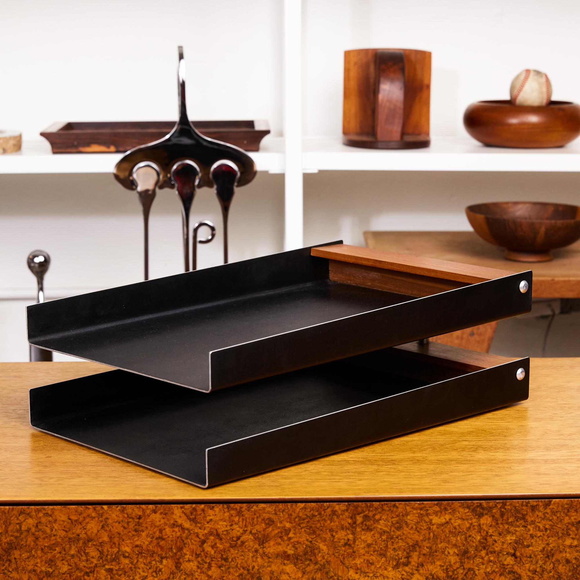 This 1950s in/out tray for office or study has two tiers, in original enameled matte black steel that rotate around a central post of brushed steel. The trays are finished with an inset back panel of solid walnut. 

Tray bottoms retain the