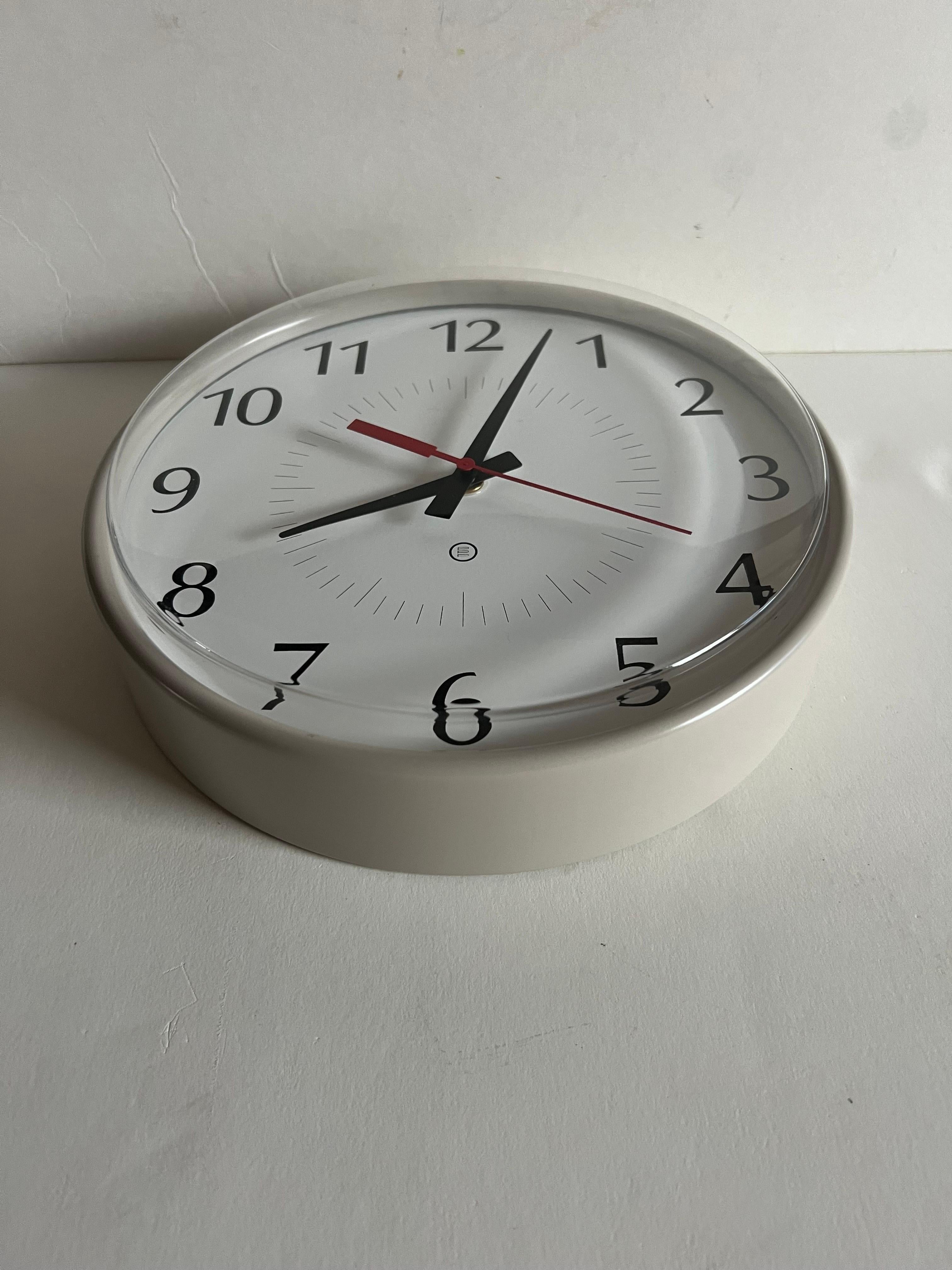 A vintage wall mount clock by Peter Pepper Products.  Circa late 20th Century. 

Taupe metal frame with white bezel; black numerals.

Quartz/battery operated.  Takes one AA battery.

Size: 10 inches W x 2.75 inches D