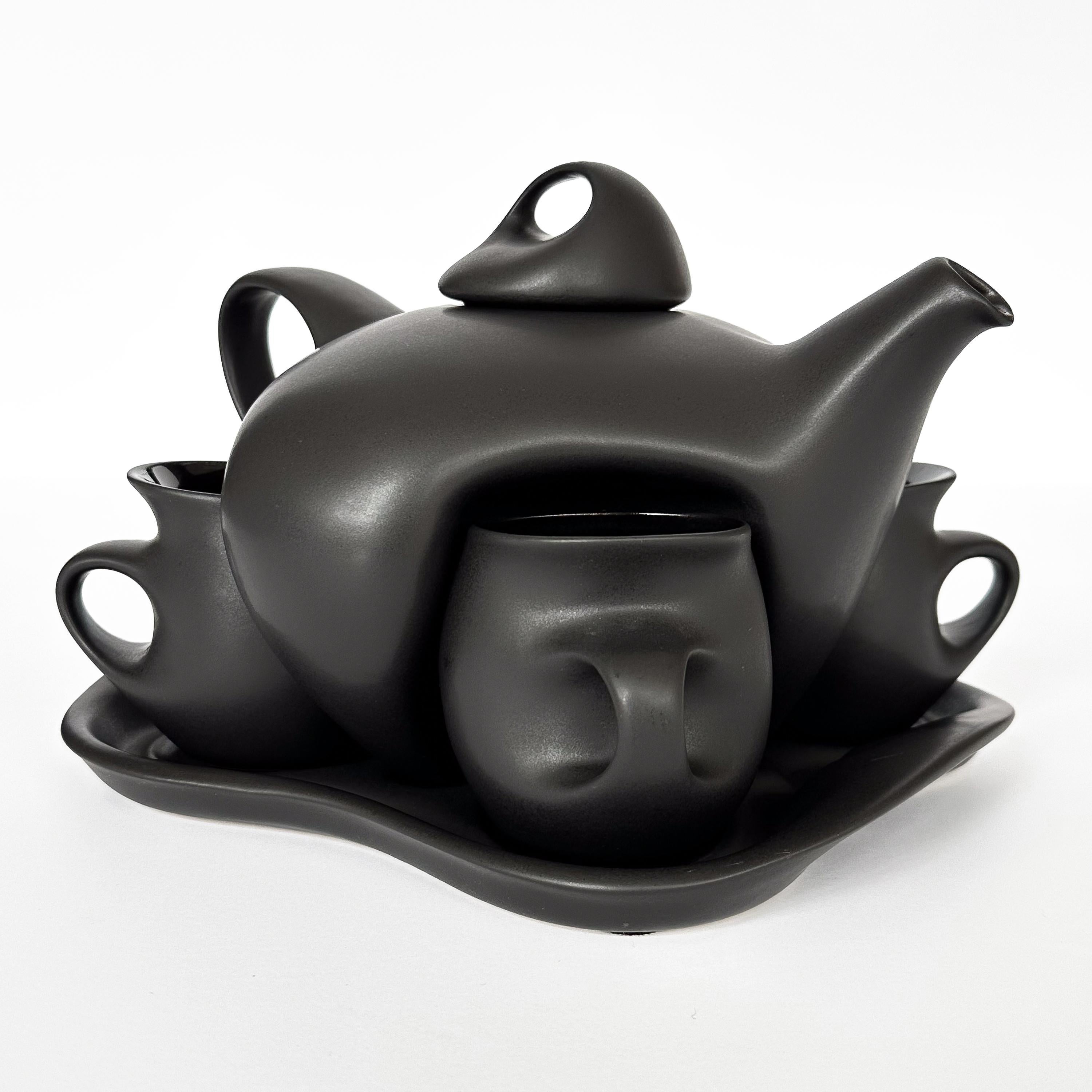 Embrace a distinctive blend of art and function with this striking black glazed ceramic tea service set, crafted by the gifted hands of Peter Saenger. His unique approach to design and form transcends the ordinary, making every sip from this set an