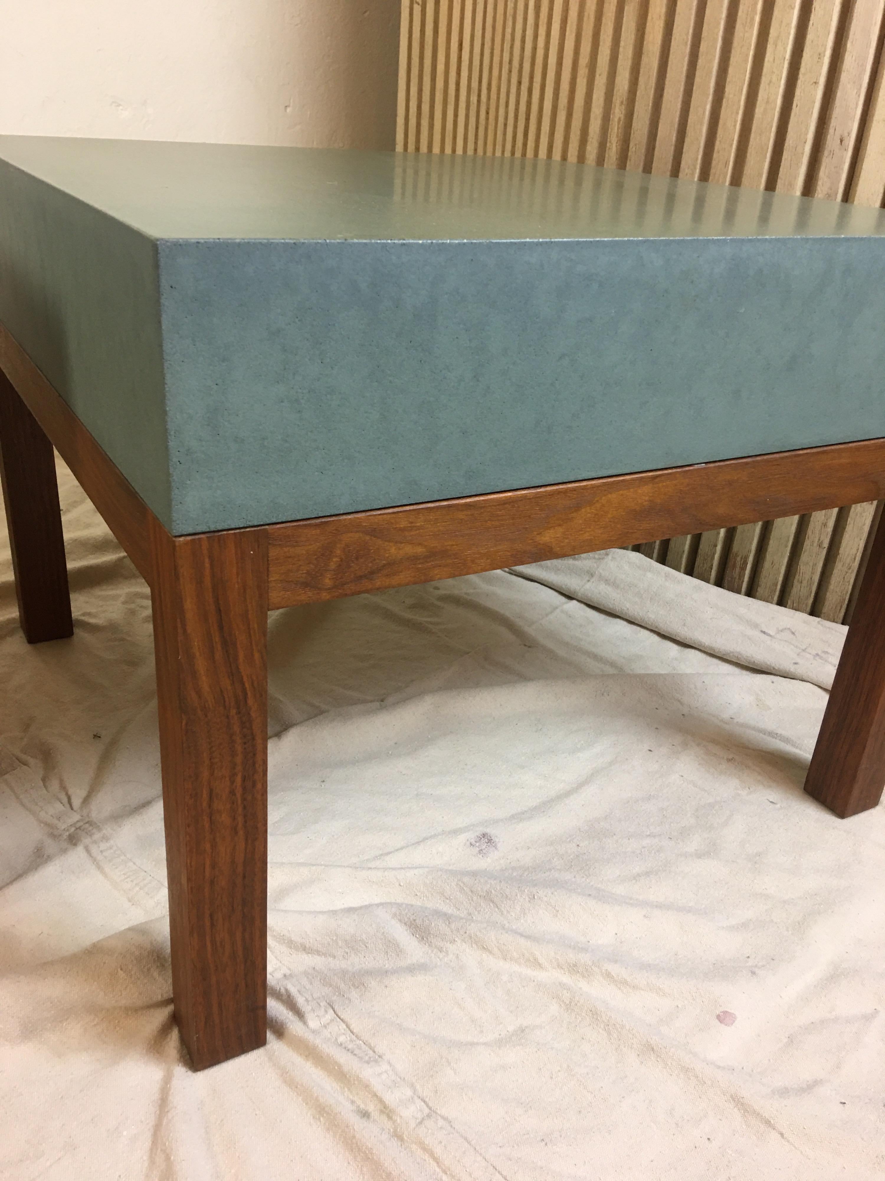 Peter Sandback pair low slung square tables made of a composite cement like material with solid walnut bases. Perfect to use as 2 end tables or together as a coffee table. Top surface is a greenish color.